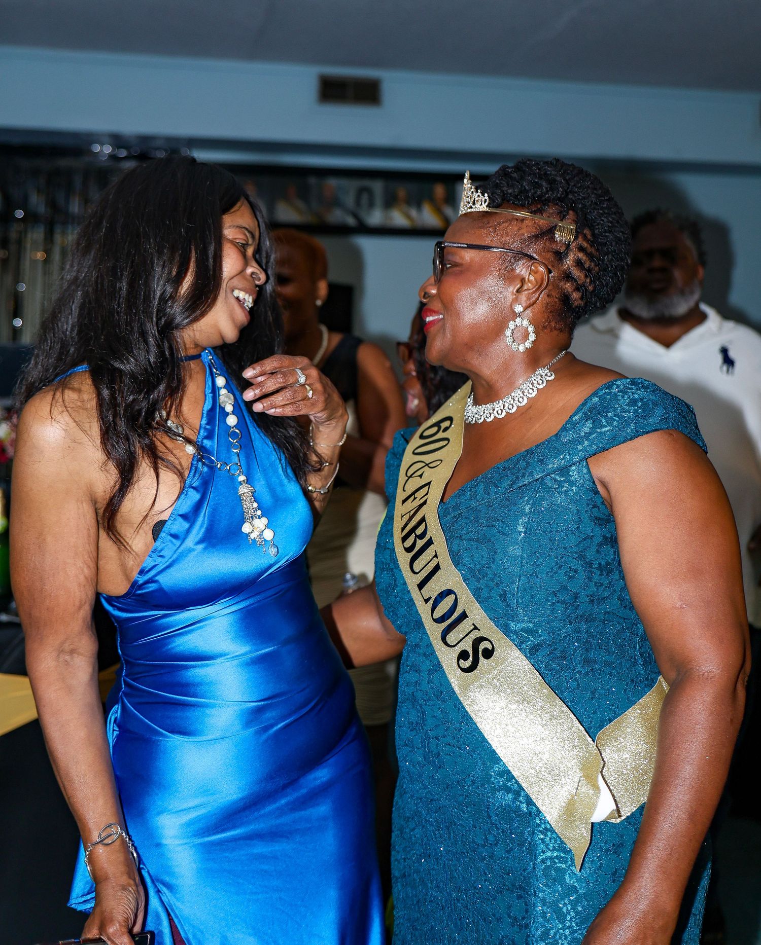 Two people in blue and teal formal attire dancing together at a celebration event.