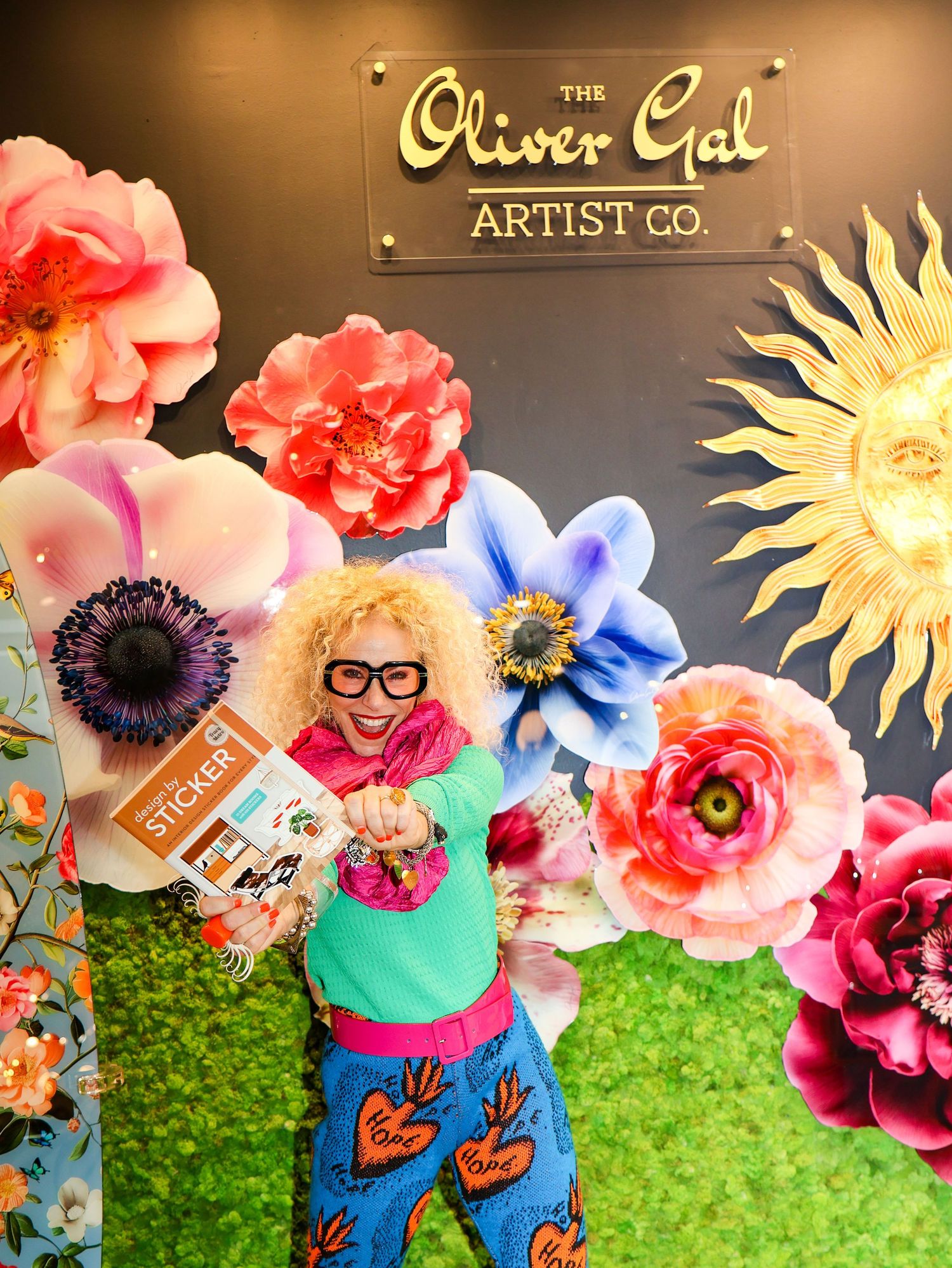 Artistic retail space with large paper flowers, sunburst decorations and green textured backdrop.