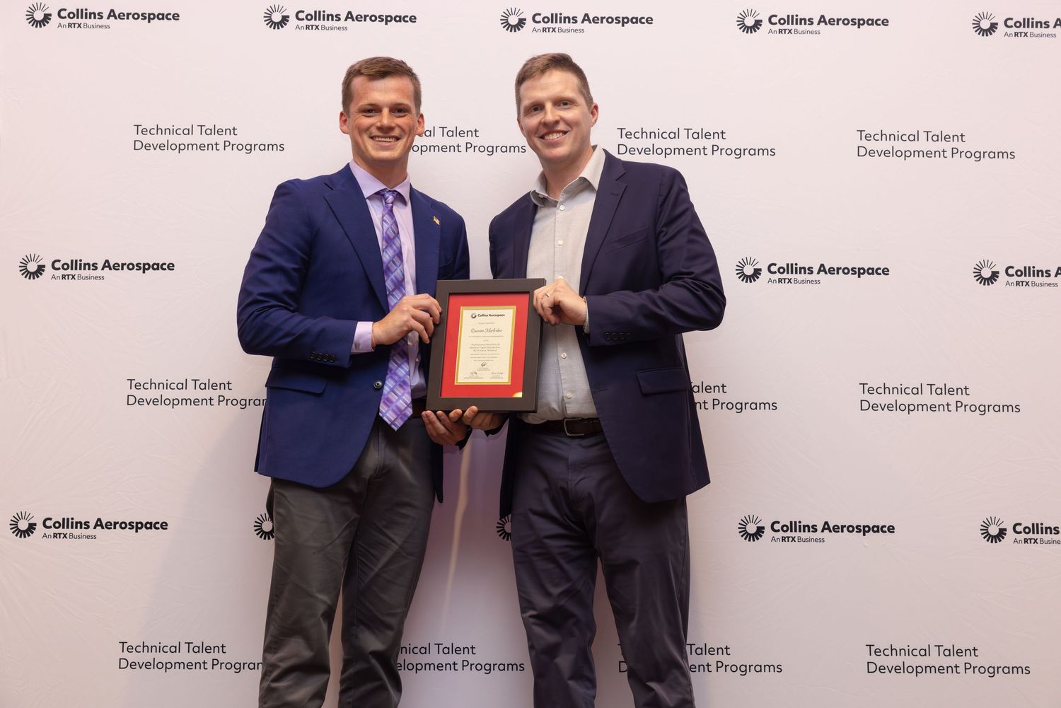 Two professionals pose with a framed award at Collins Aerospace Technical Talent Development Programs event.