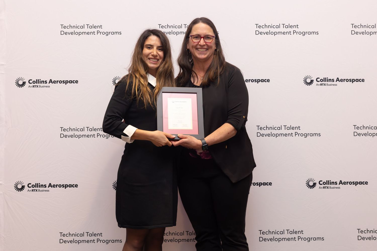 Two women hold a framed certificate at Collins Aerospace Technical Talent Development Programs awards event.