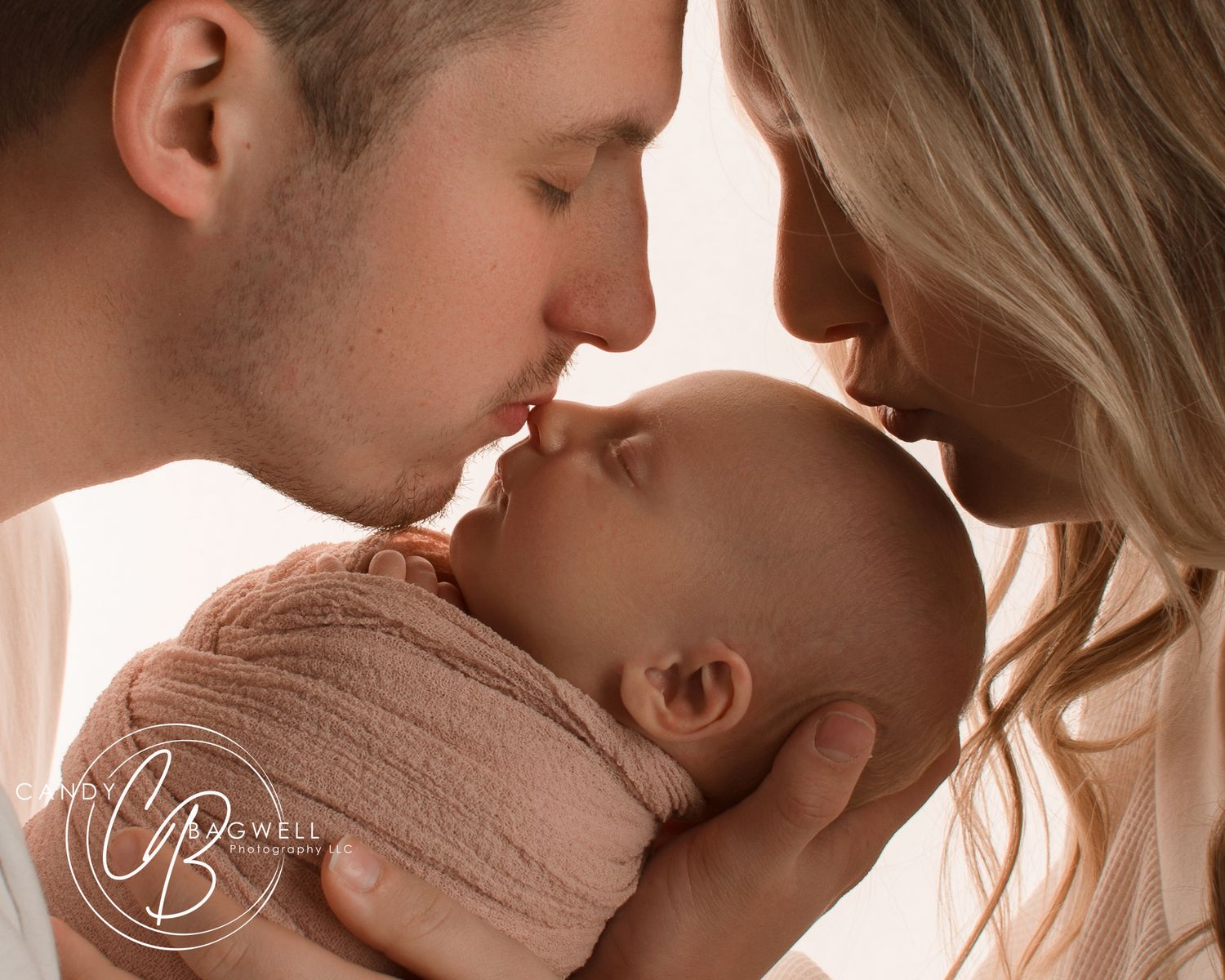 Tender newborn portrait of parents kissing their baby by Candy Bagwell Photography, serving Fletcher, Asheville, and Western NC.