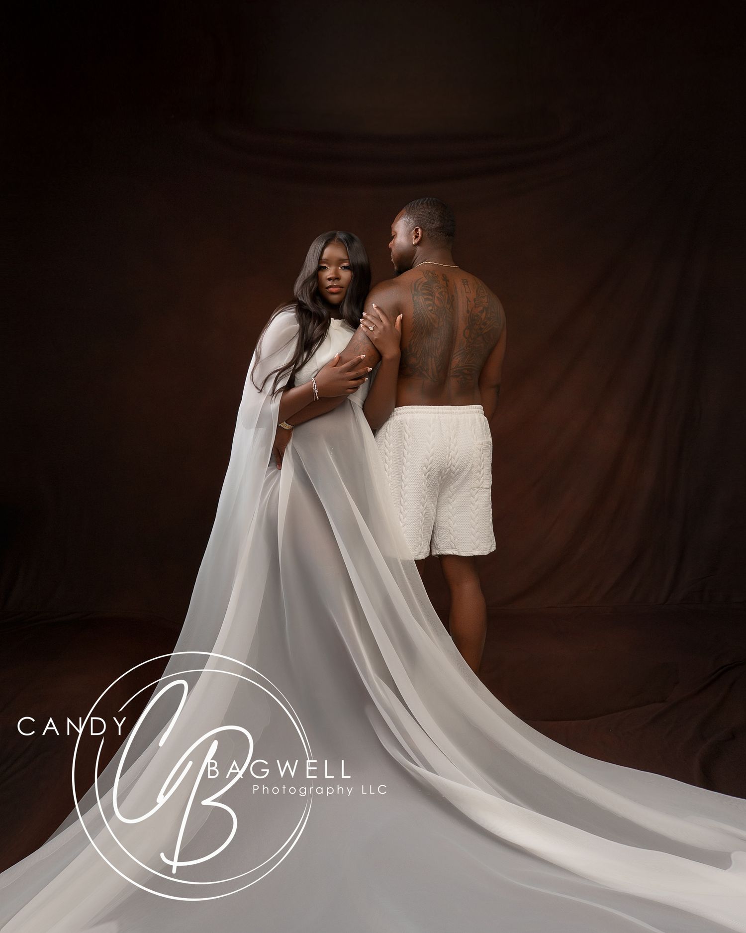 Luxury couples maternity portrait featuring a flowing white gown and dramatic studio styling by Candy Bagwell Photography in Fletcher, NC.