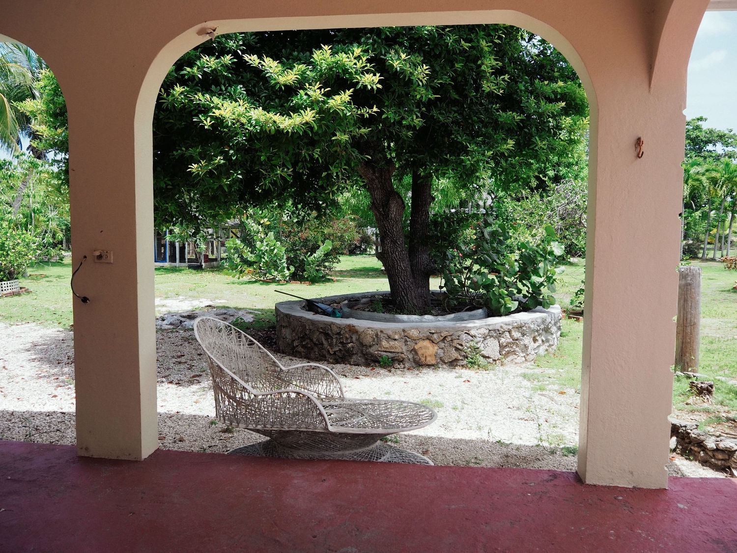 A covered outdoor patio area with multiple hammocks strung between columns overlooking a green garden landscape.