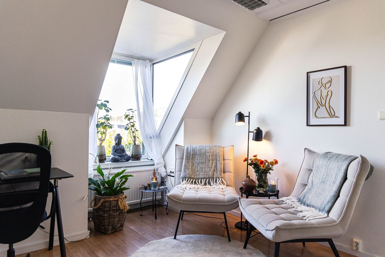 Modern attic bedroom with sloped ceiling features white walls, skylight windows, and minimalist furniture arrangement.