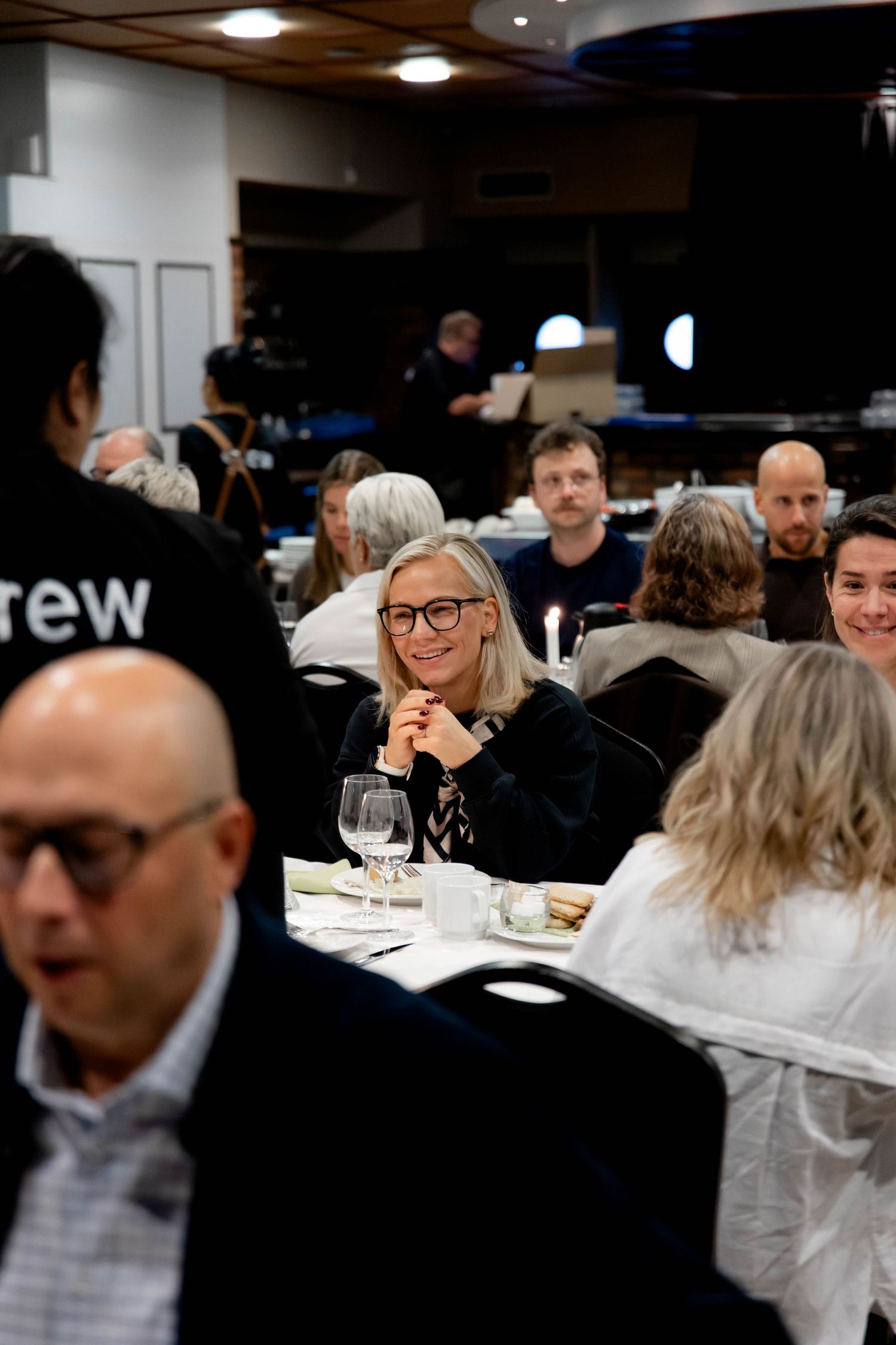 A group of people sitting at tables during a business meeting or conference event in an indoor space.