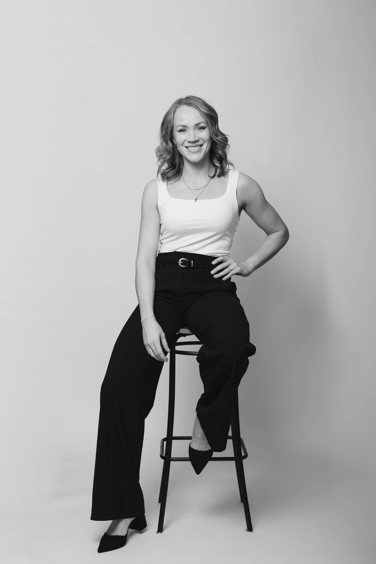 Black and white studio portraits of someone posing casually on a chair against a plain background.