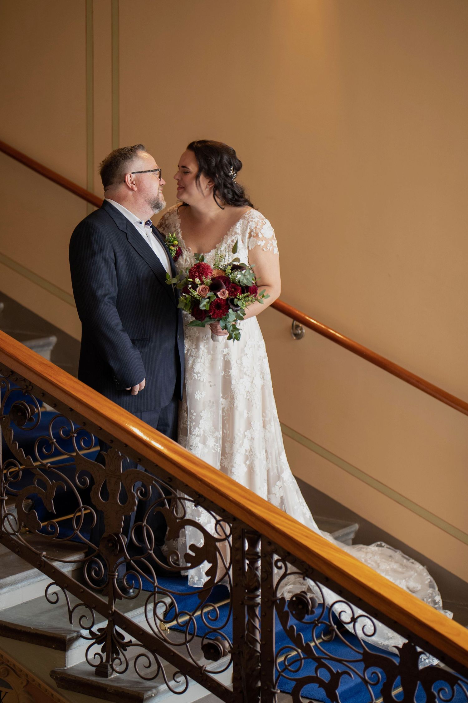 Couple sharing romantic moments on an elegant staircase with ornate iron railings during their wedding photoshoot.
