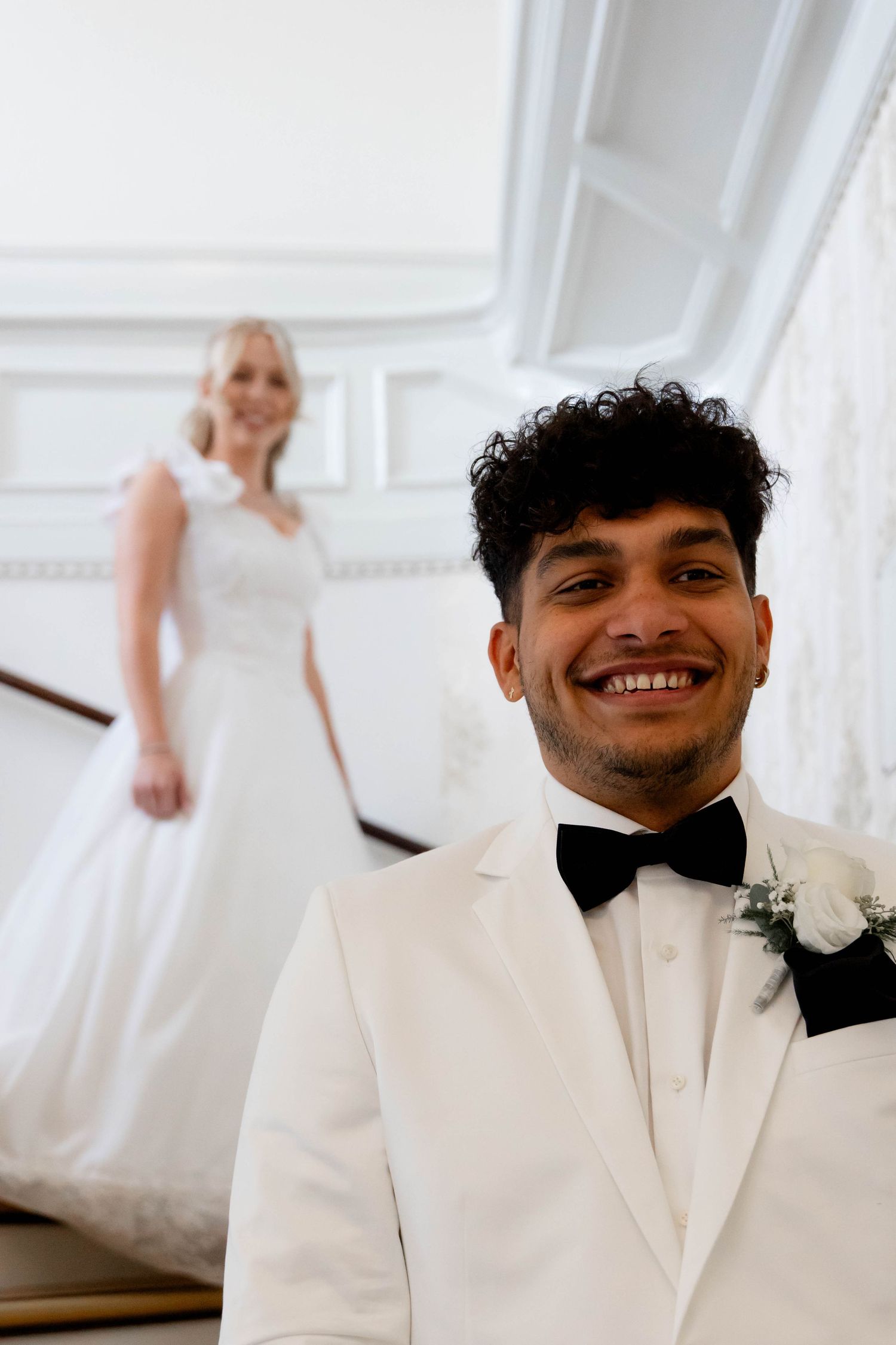A series of wedding photos showing a couple in white formal attire walking down elegant white stairs.