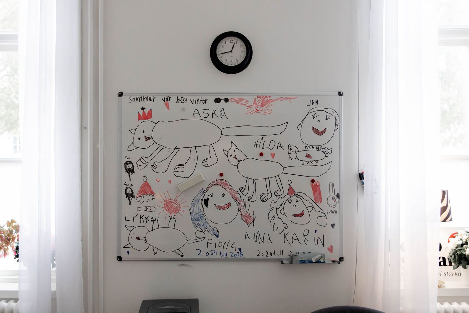 A whiteboard wall displays multiple hand-drawn illustrations and sketches in red and black markers.