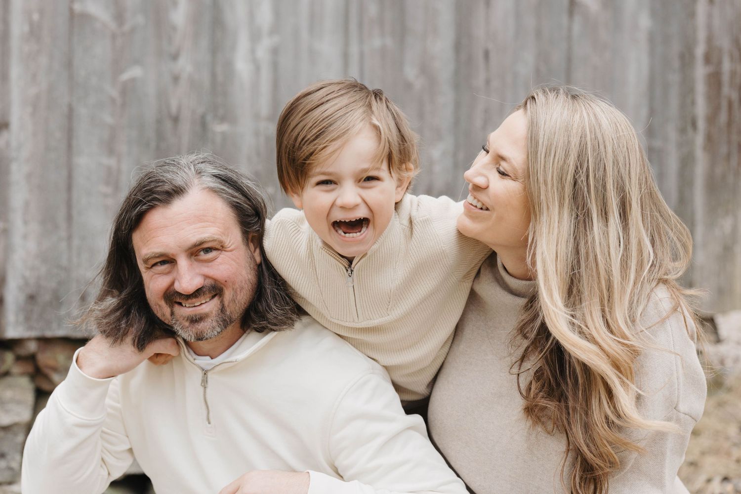 A collage of candid family portraits showing joyful moments and laughter against a rustic wooden backdrop.