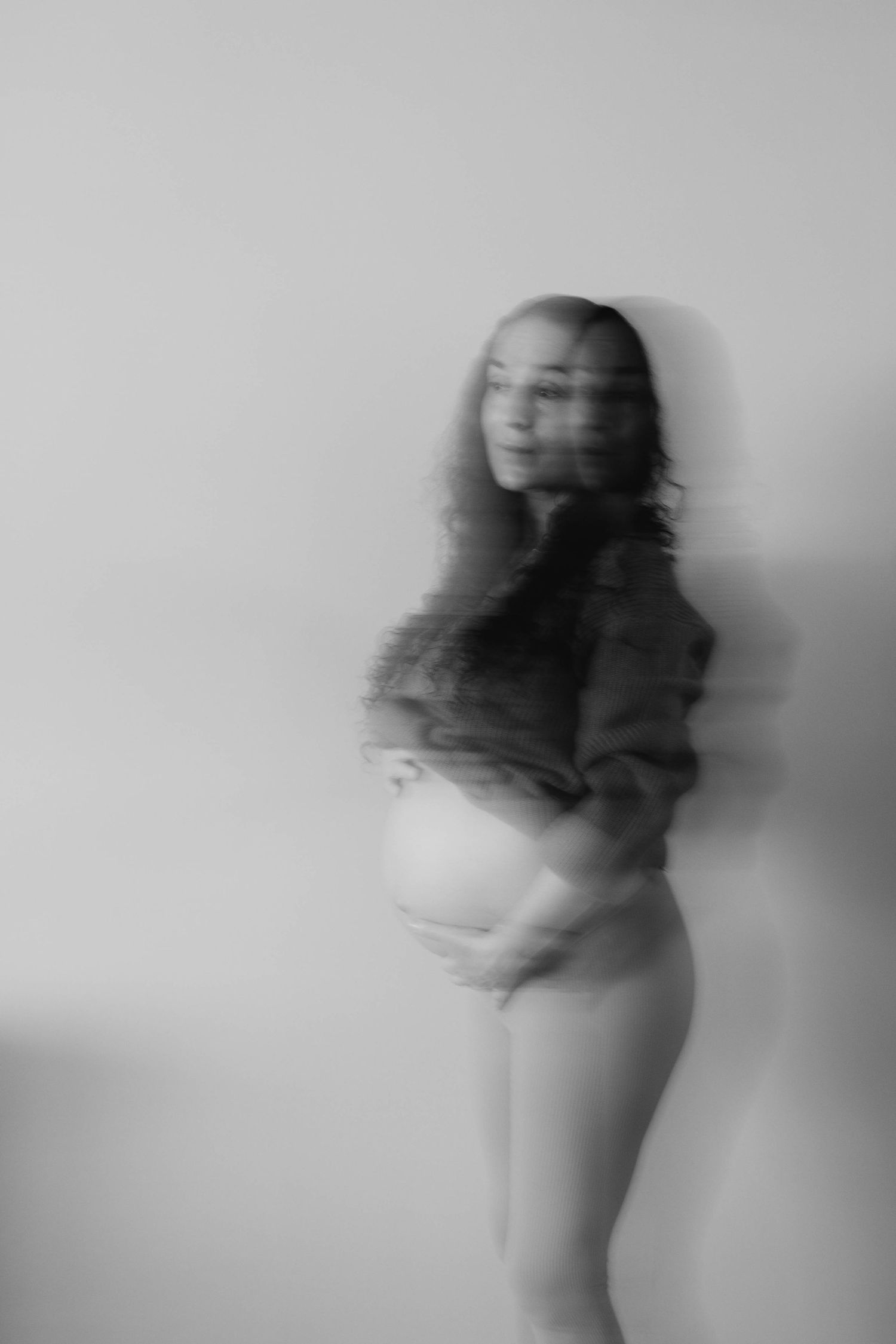 A series of blurry black and white photos showing abstract motion and movement of a figure against a light background.