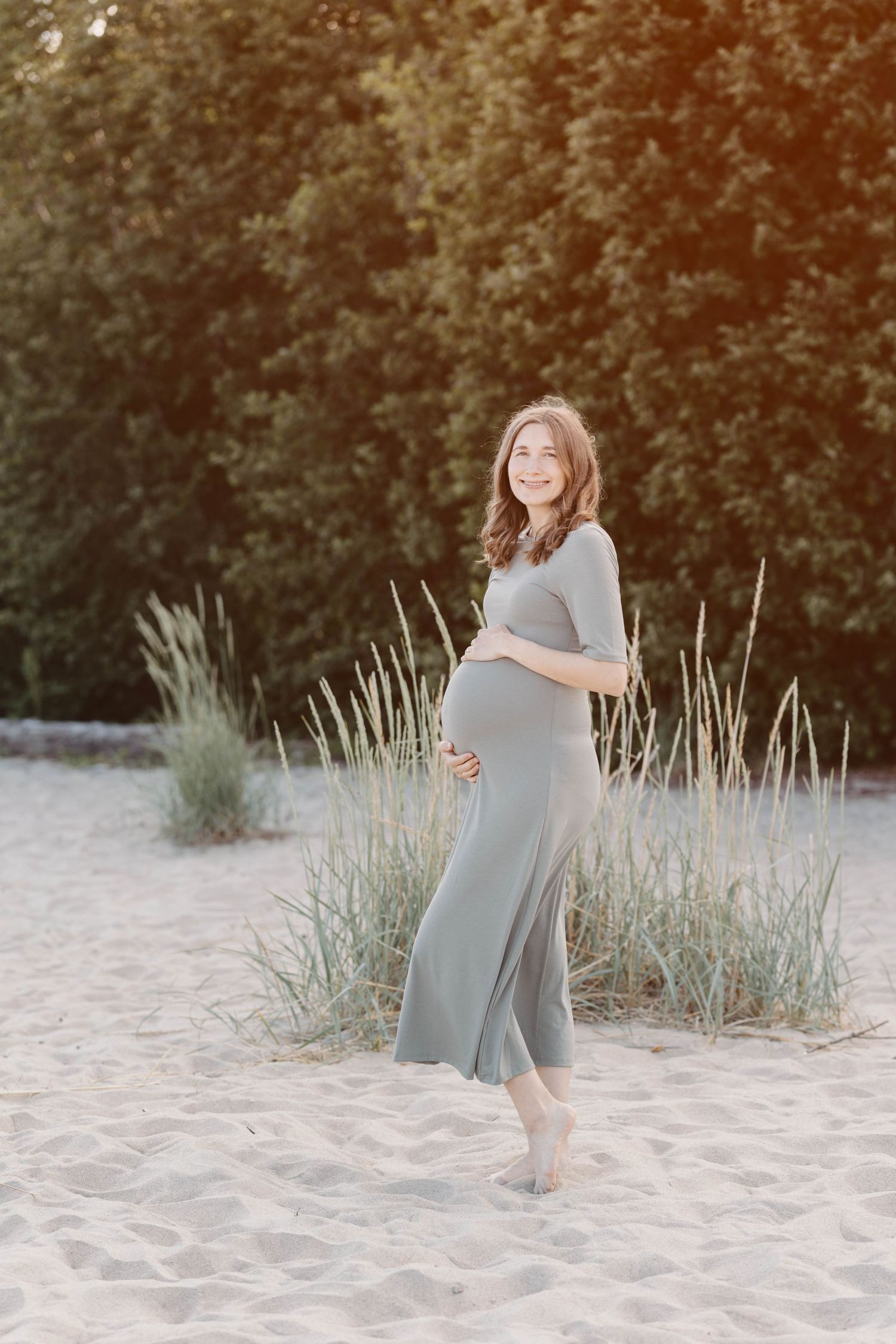A romantic beach photoshoot sequence showing a couple in grey outfits embracing on sandy dunes at sunset.