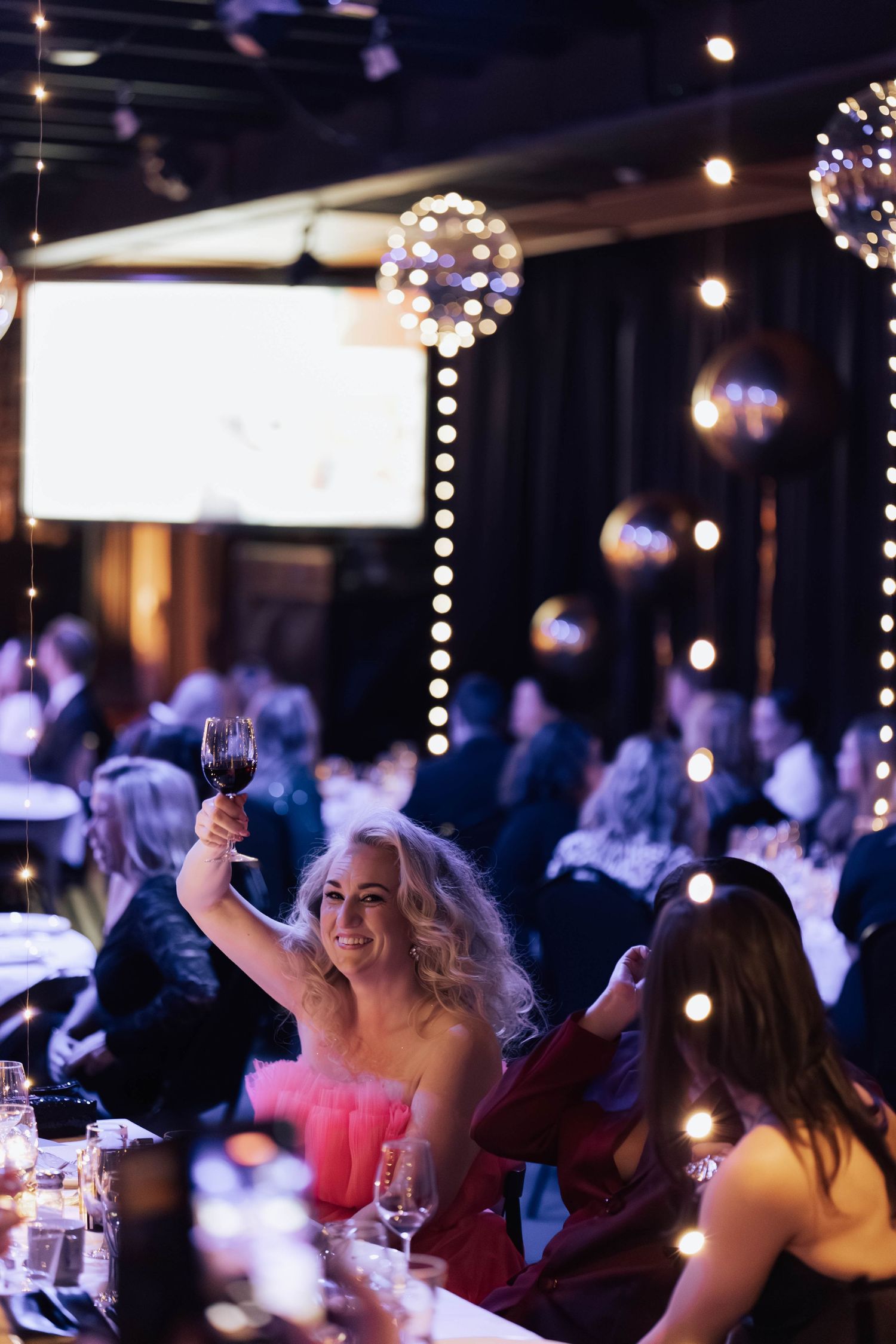 People enjoying a festive evening event with string lights and disco balls creating an intimate party atmosphere.