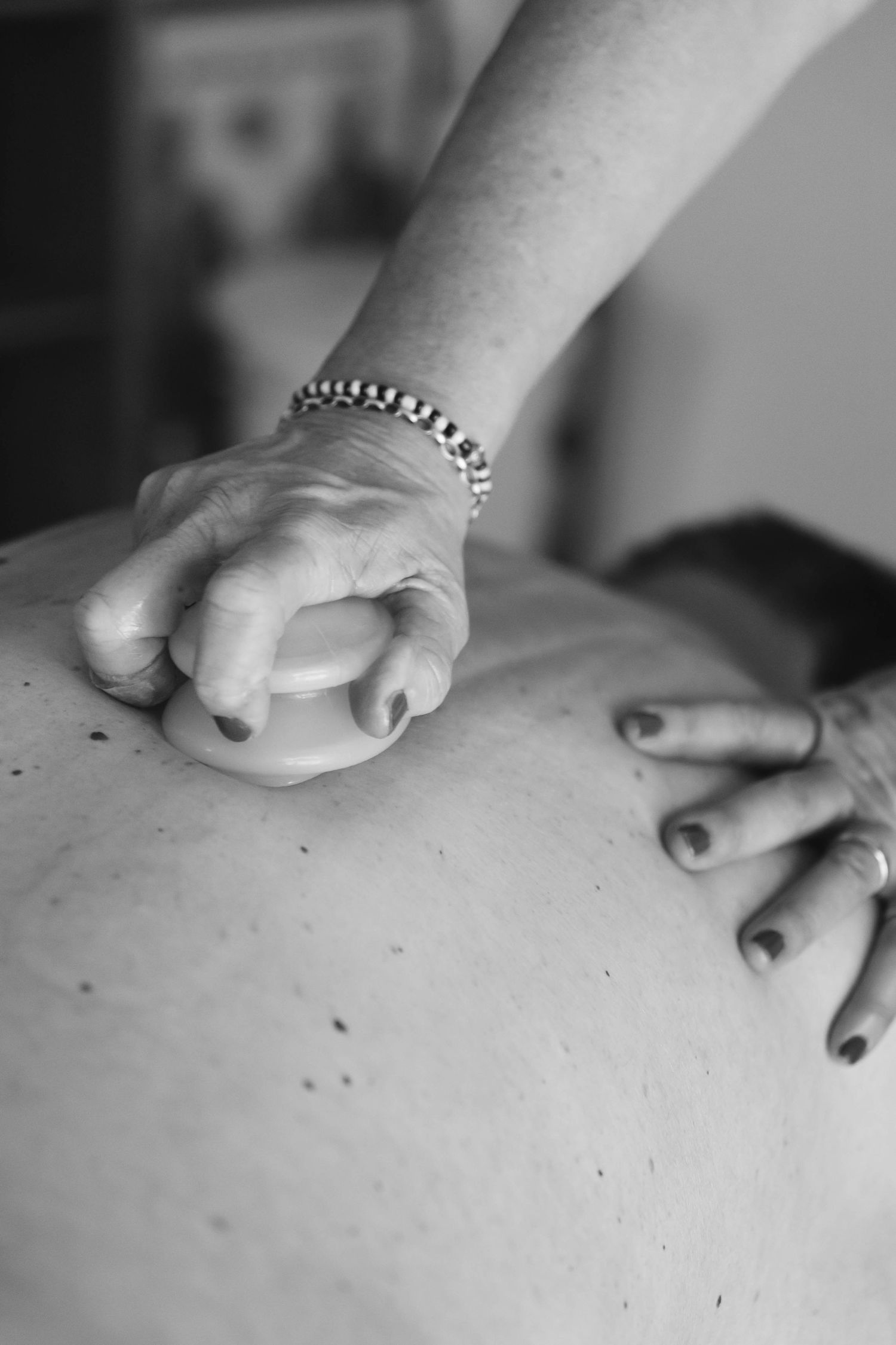 A sequence of black and white photographs showing hands performing a therapeutic massage on someone's back.