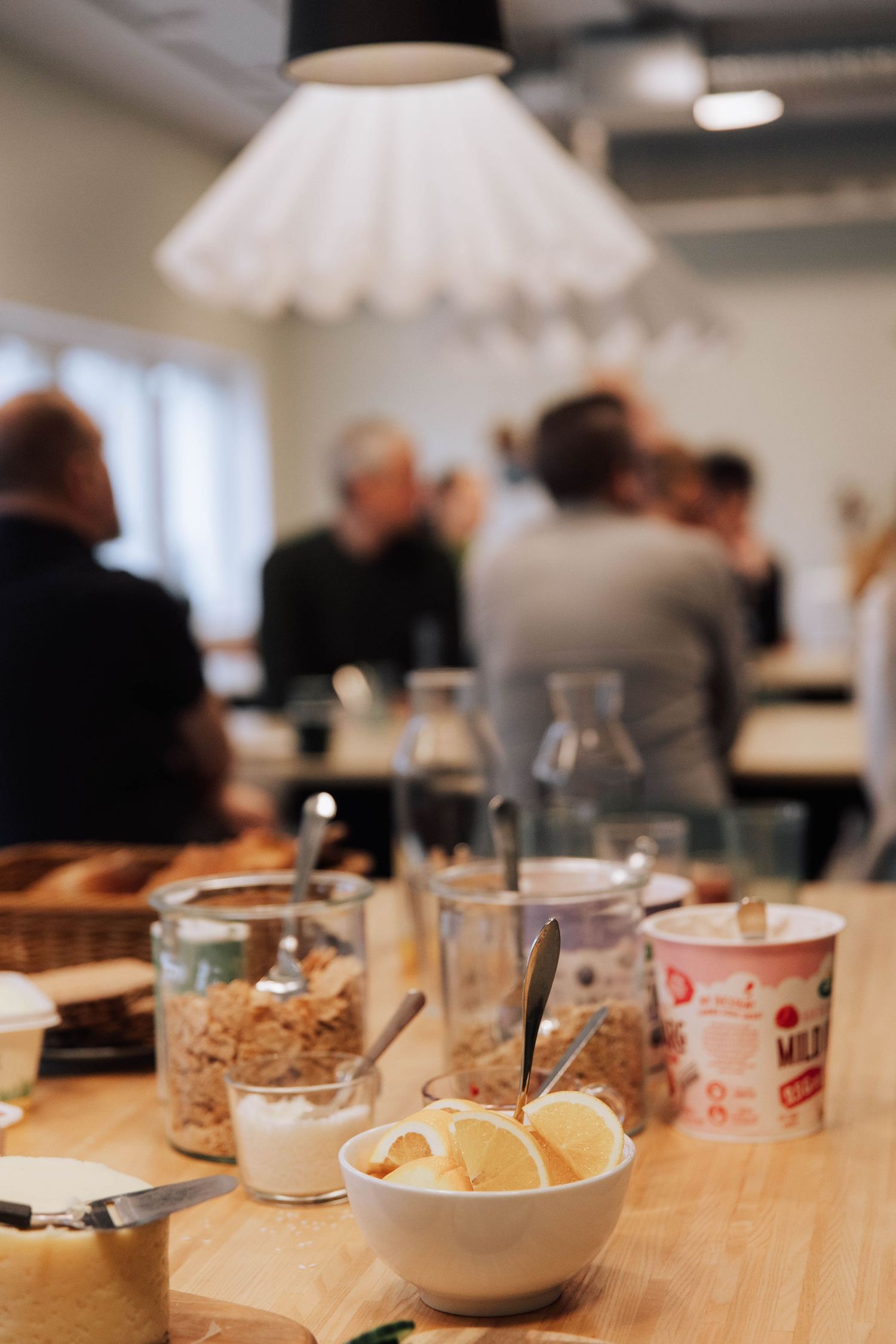 A series of food items and snacks arranged on a wooden table at what appears to be a casual gathering or meeting.