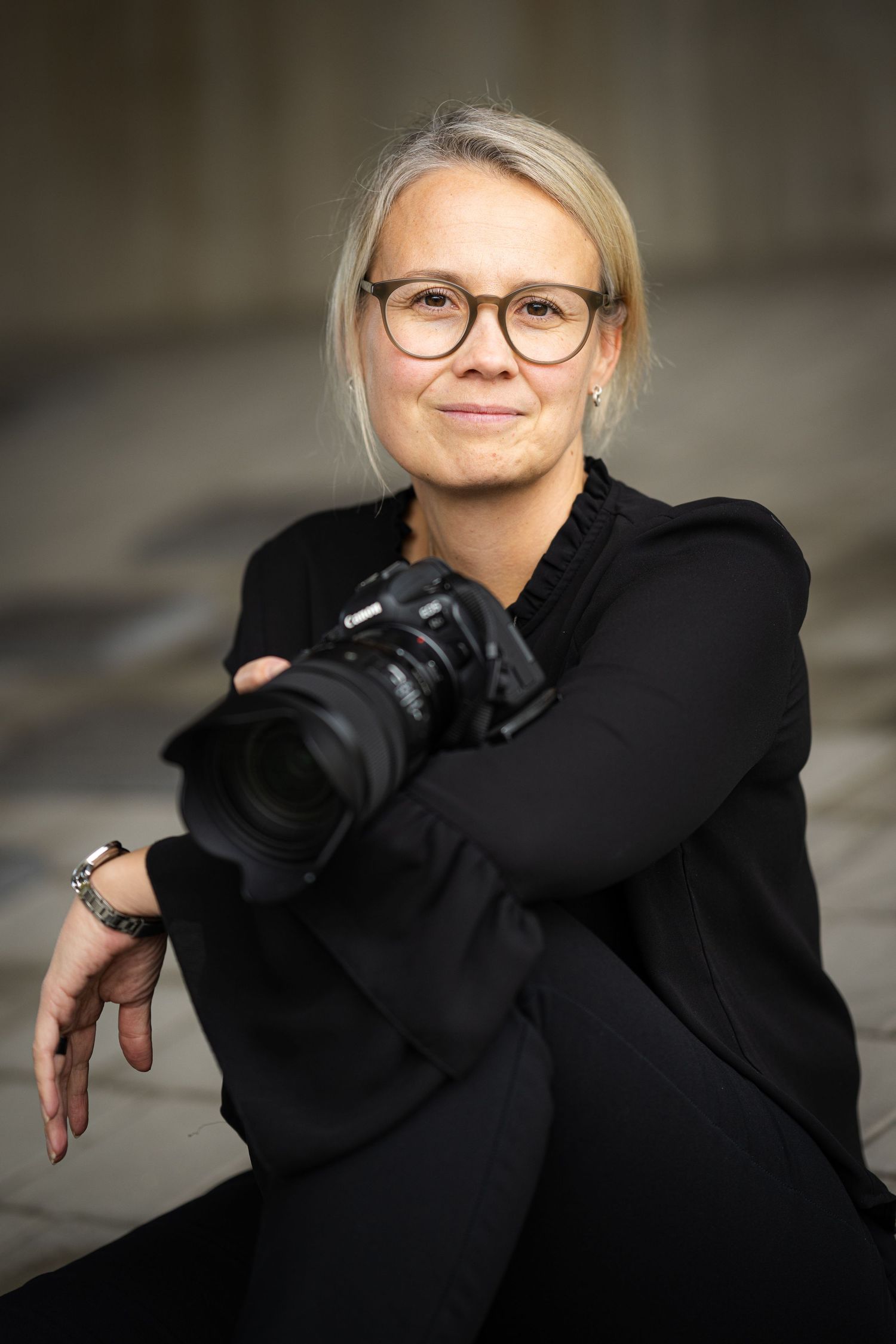 Professional headshot series of a person in a black sweater with glasses showing different expressions and poses.