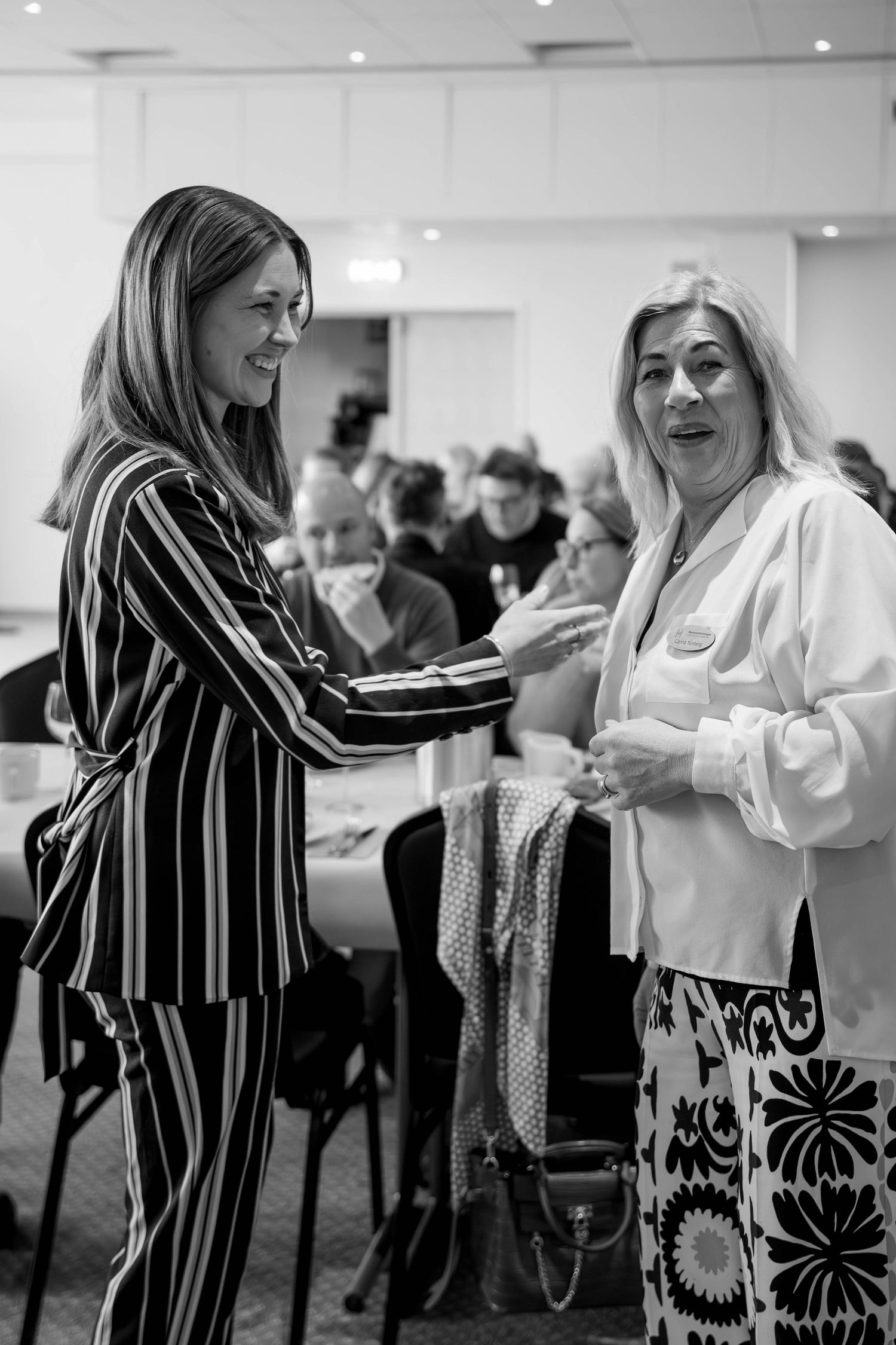 Black and white photos show people laughing and interacting at a social gathering in a bright indoor space.