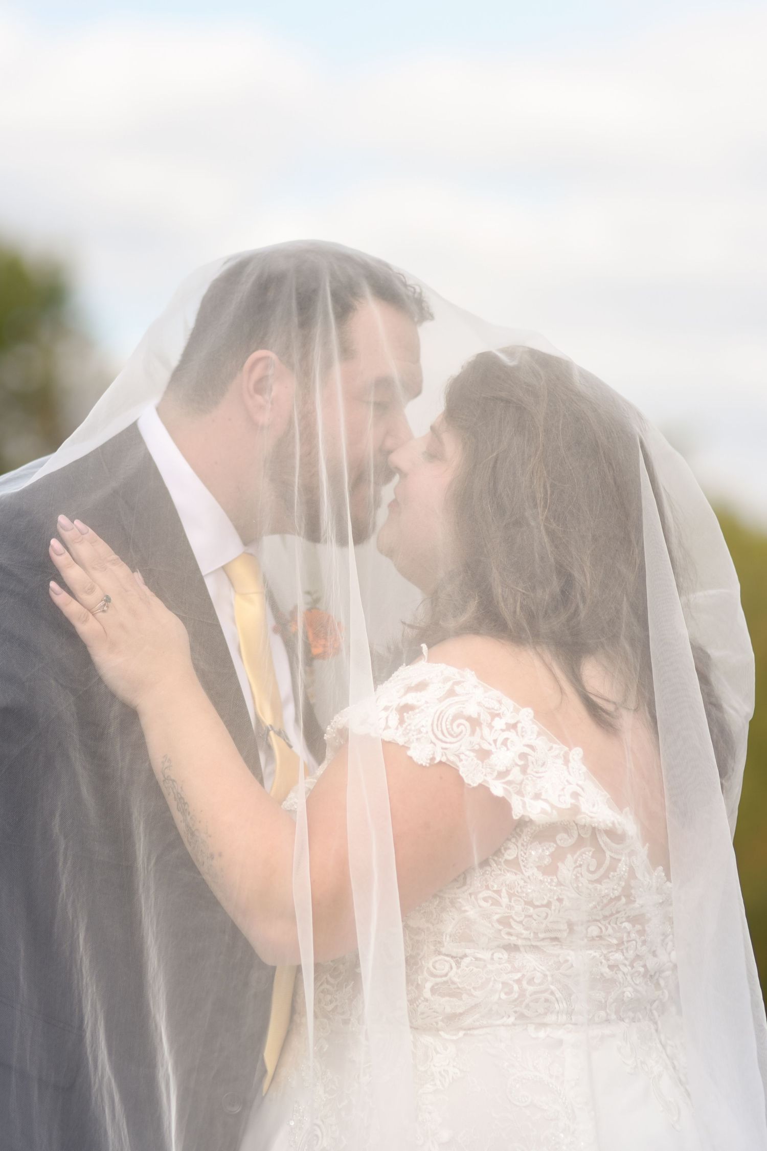 Groom and bride kissing below the veil