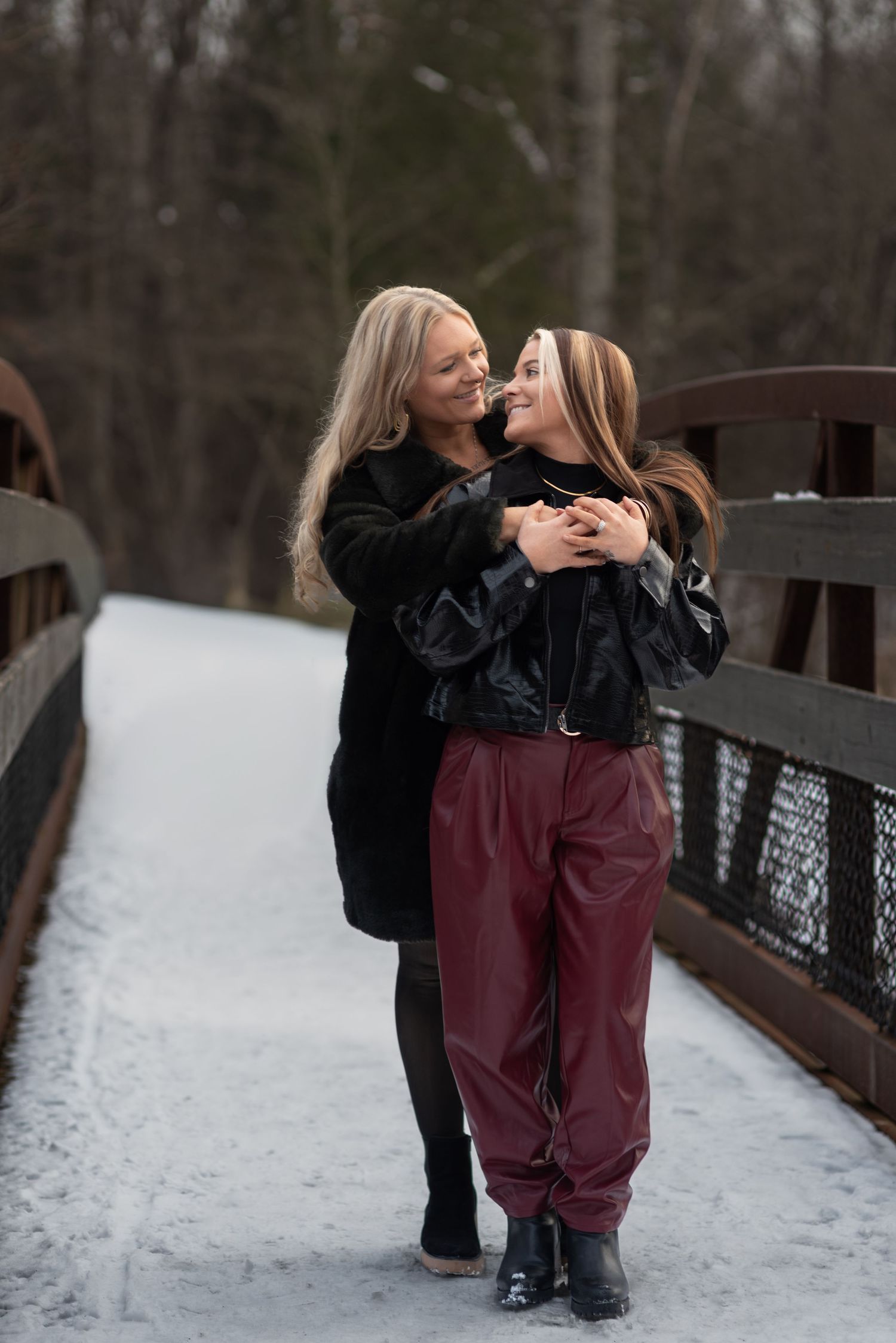 Wives looking at each other lovingly on a snowy bridge