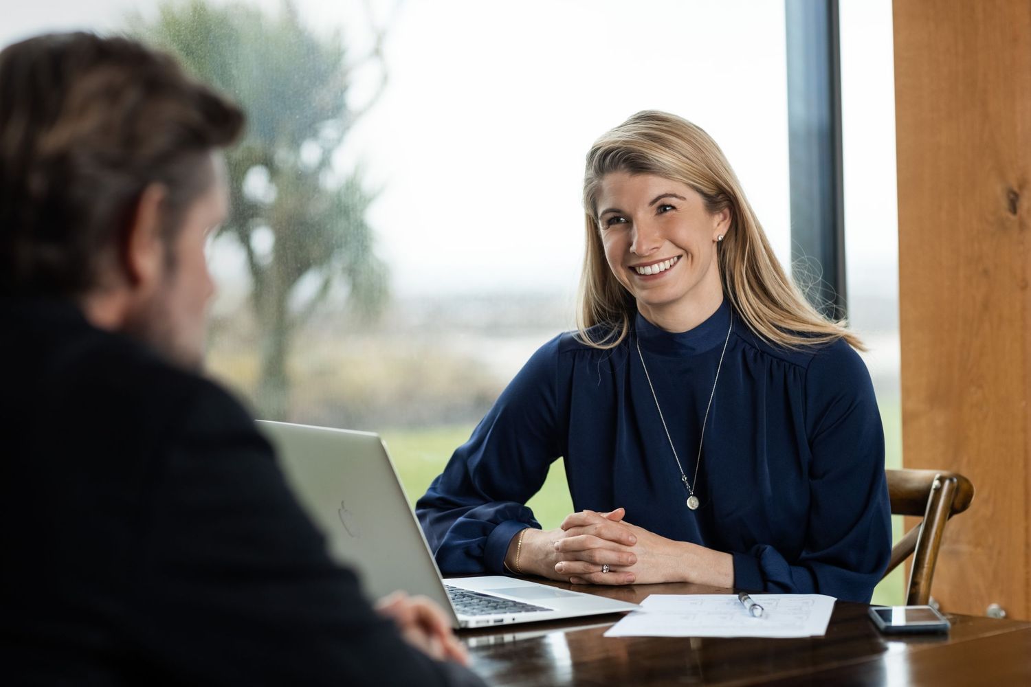 Two professionals having a business meeting at a table with a laptop in a bright office setting.