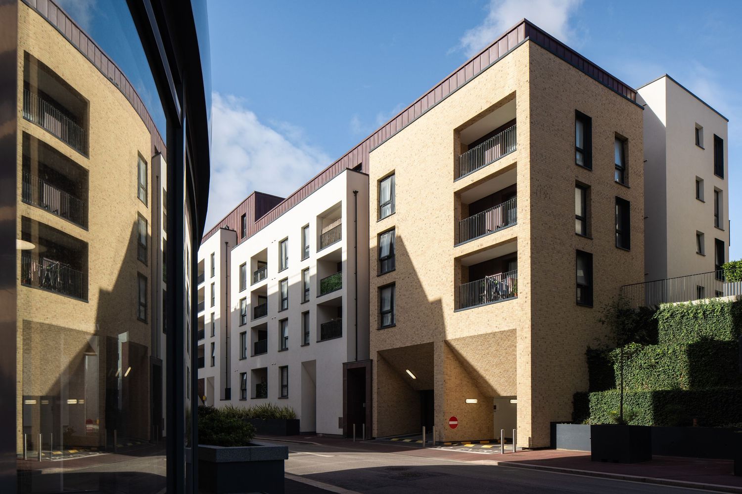 Modern residential complex with beige and white facades featuring multiple balconies and geometric design.