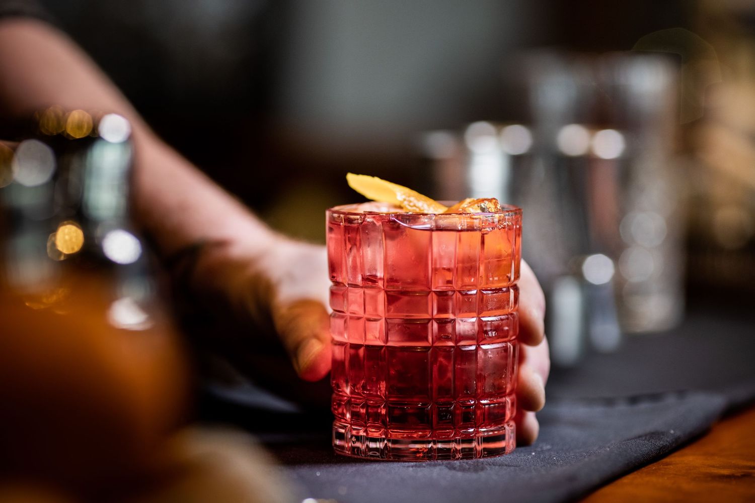 Red craft cocktails served in crystal glasses on a black stone surface.