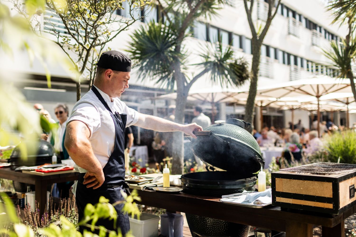 Chef grilling and cooking at an outdoor kitchen station with professional equipment.