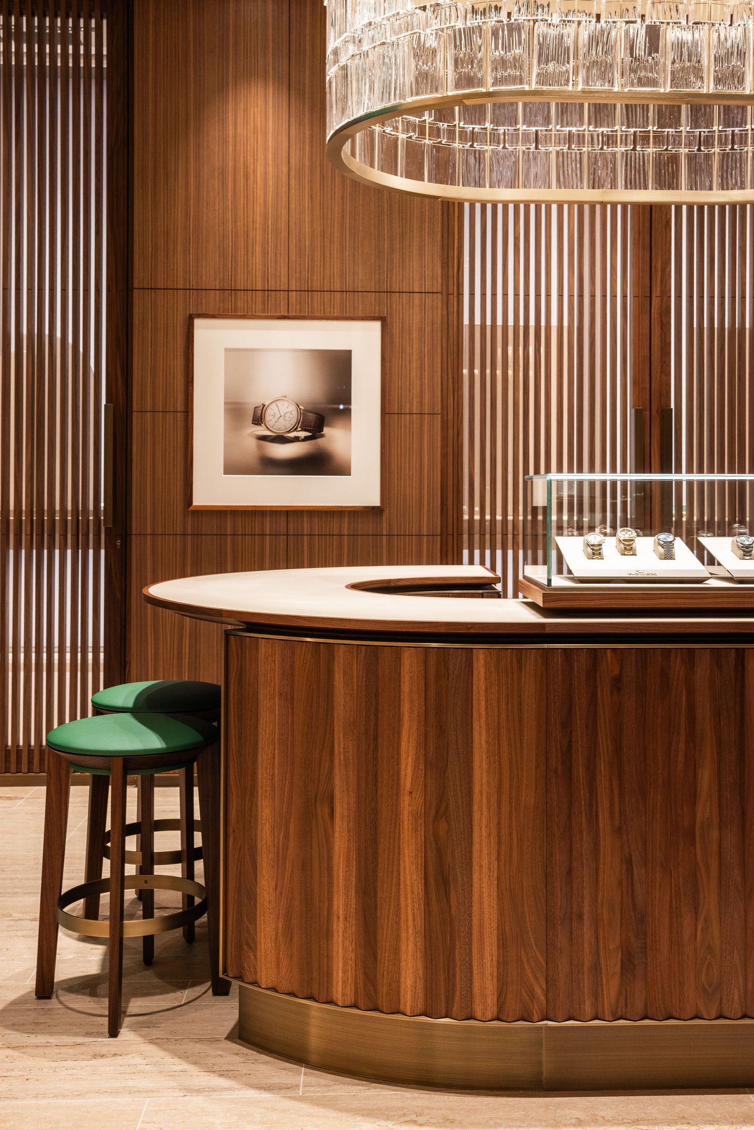 High-end watch boutique featuring wood paneling and crystal chandelier with circular display cases.