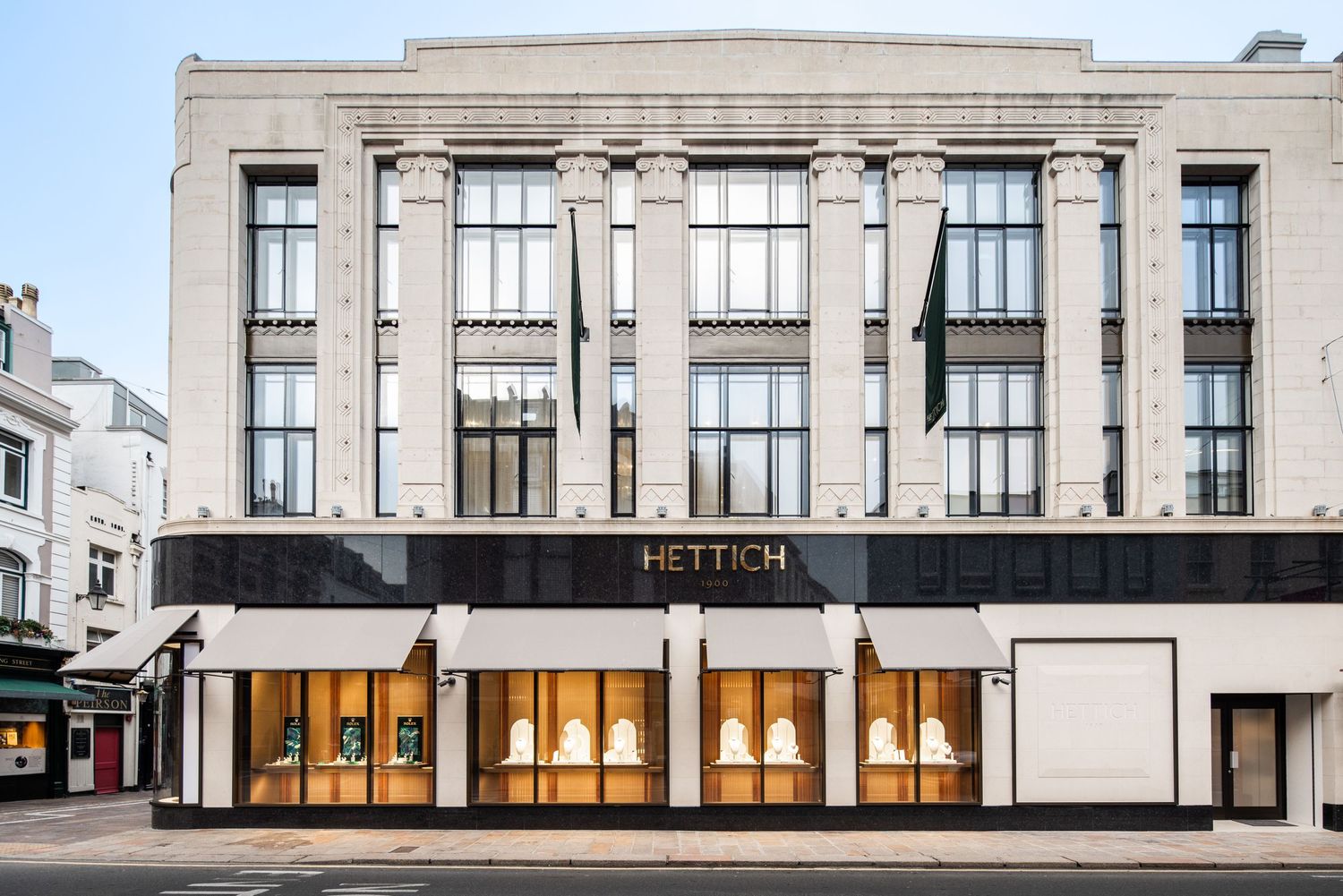 Art deco style limestone facade of a luxury retail building with large display windows.