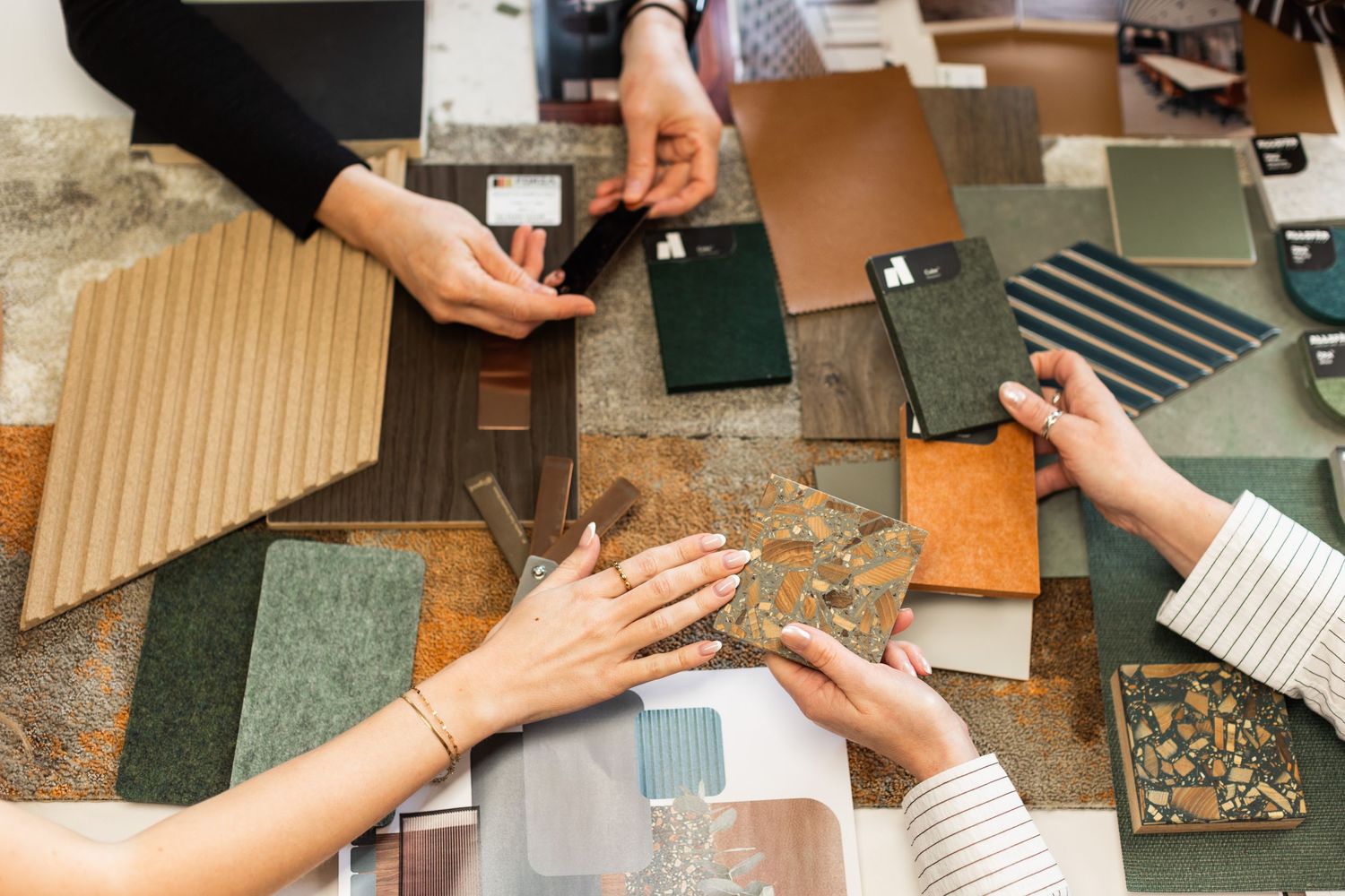 Close-up shots of hands reviewing material and fabric swatches on a work surface at Axis Mason.