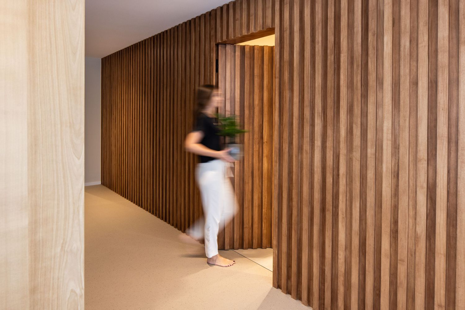 Wooden slat wall detail in a modern hallway with natural lighting.