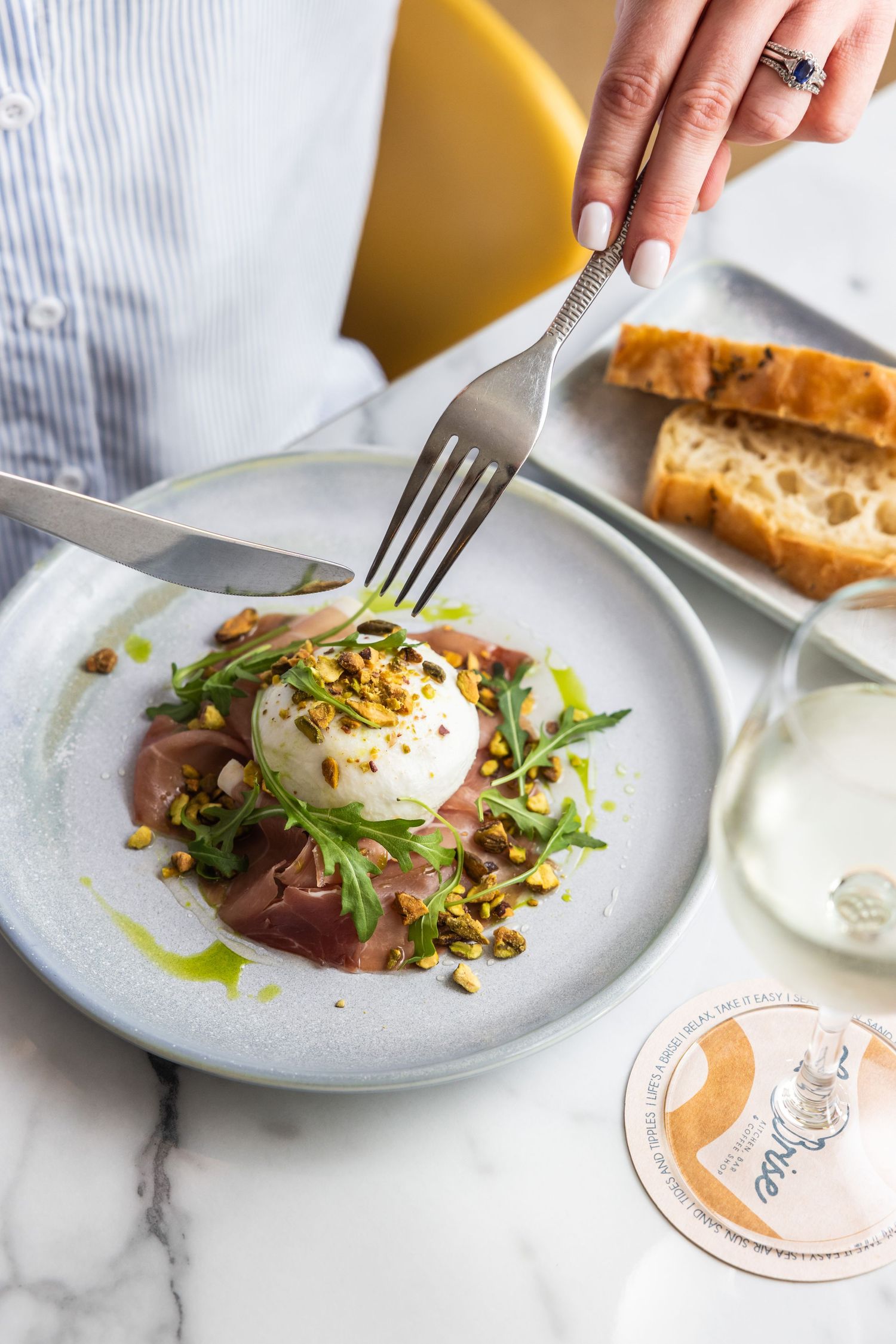 Three plated dishes of burrata with beets, microgreens and toasted nuts served on white plates against marble surface.