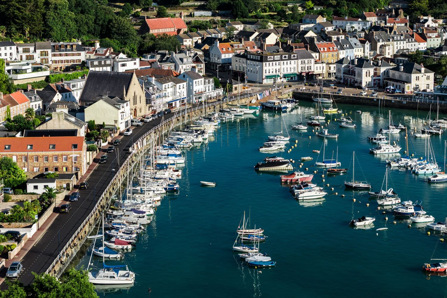Panoramic aerial view of a marina filled with boats and waterfront buildings.