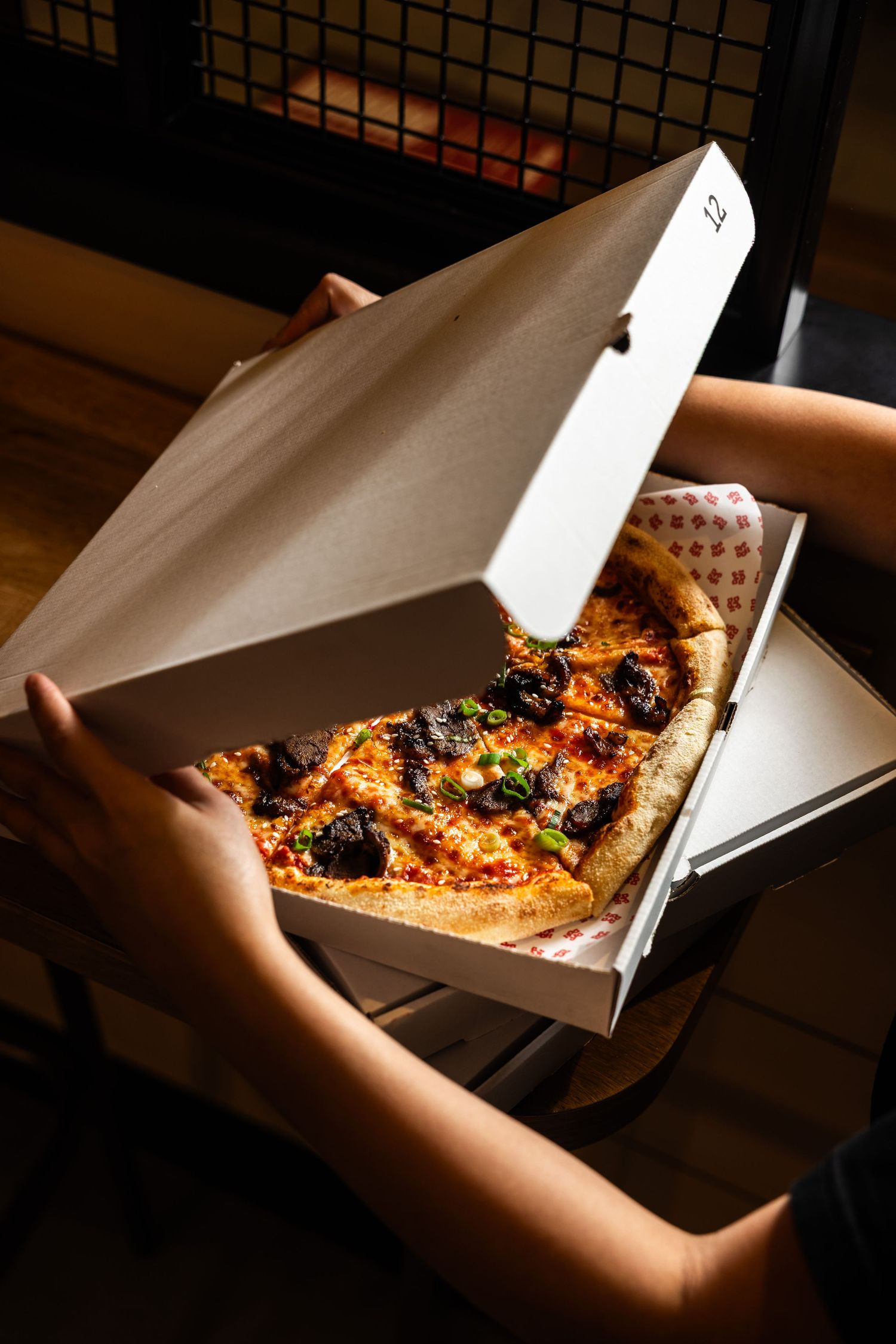 Freshly baked pizza with toppings in an opened white delivery box.