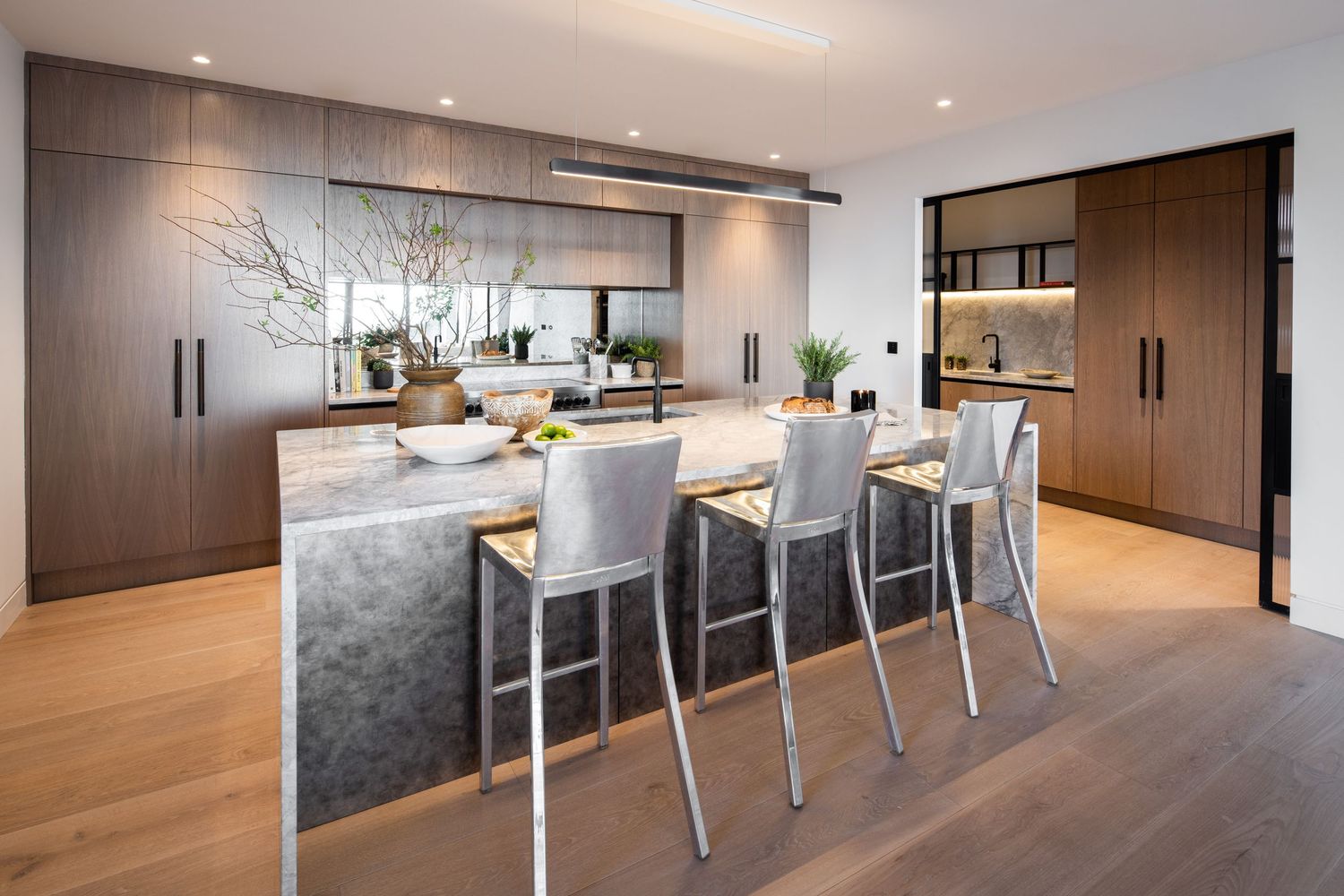 Modern open concept dining area with wooden cabinetry and sleek gray chairs.