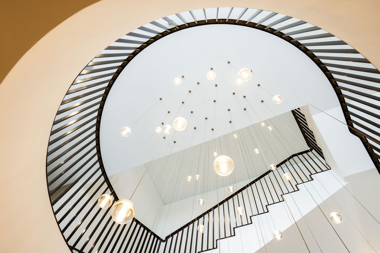 Spiral staircase with black railings and white walls illuminated by natural light from above.