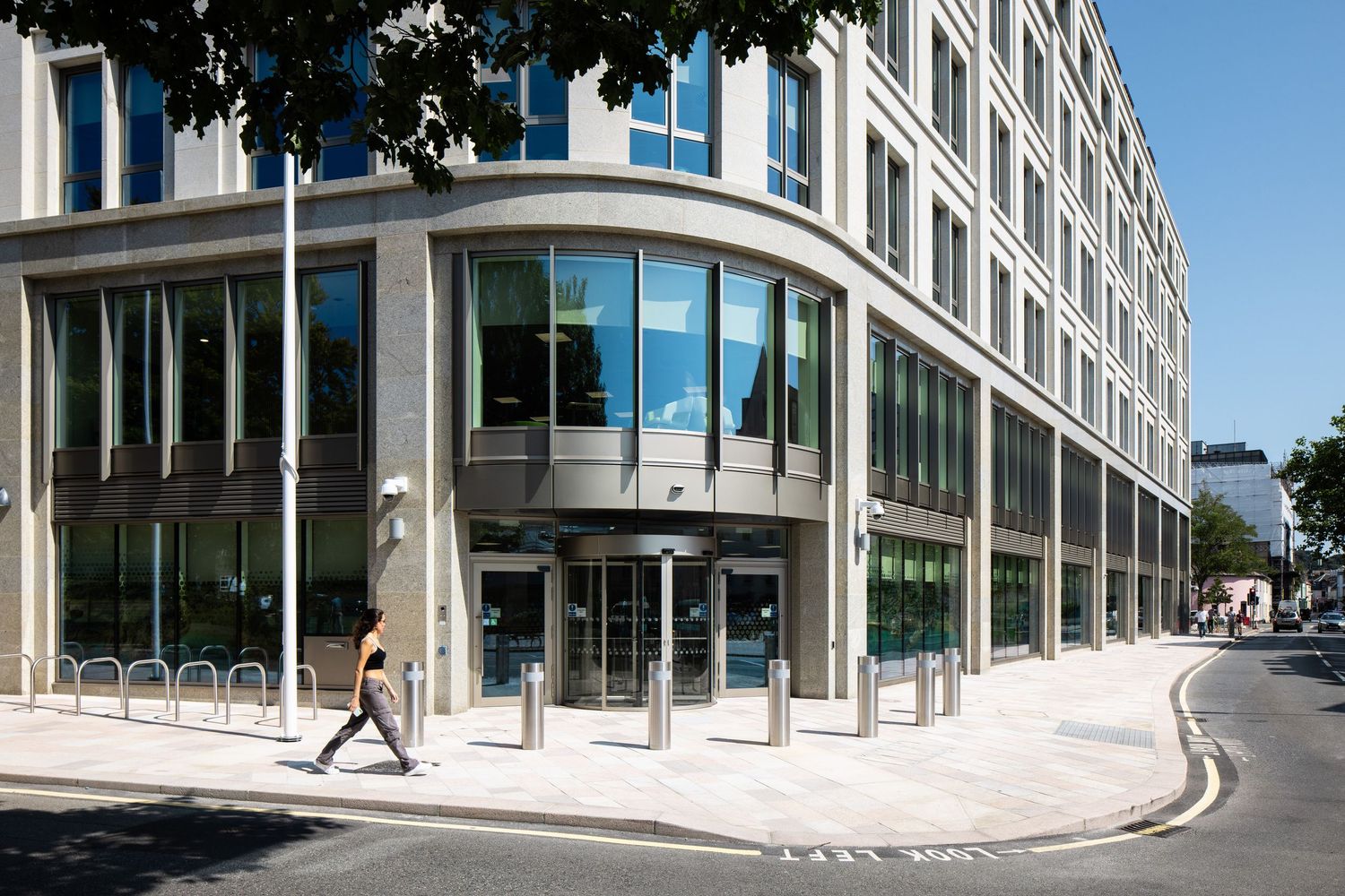 Corner view of a modern office complex with floor-to-ceiling windows and curved architectural design.