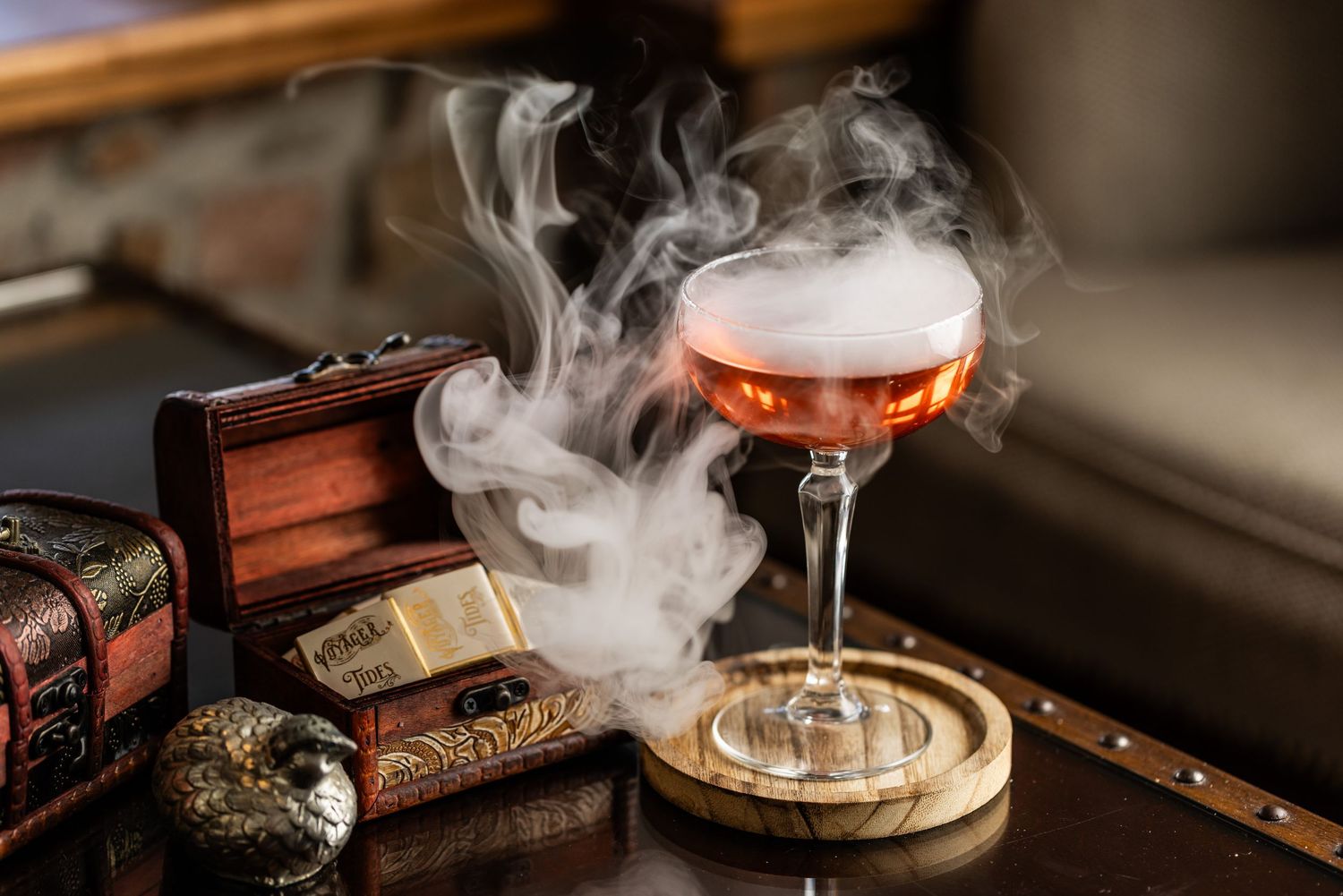 Smoky cocktail presentation with dramatic lighting and vintage books in the background.