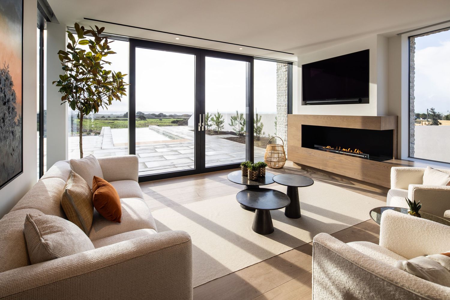Modern living room with panoramic windows, linear fireplace, and comfortable seating overlooking scenic views.