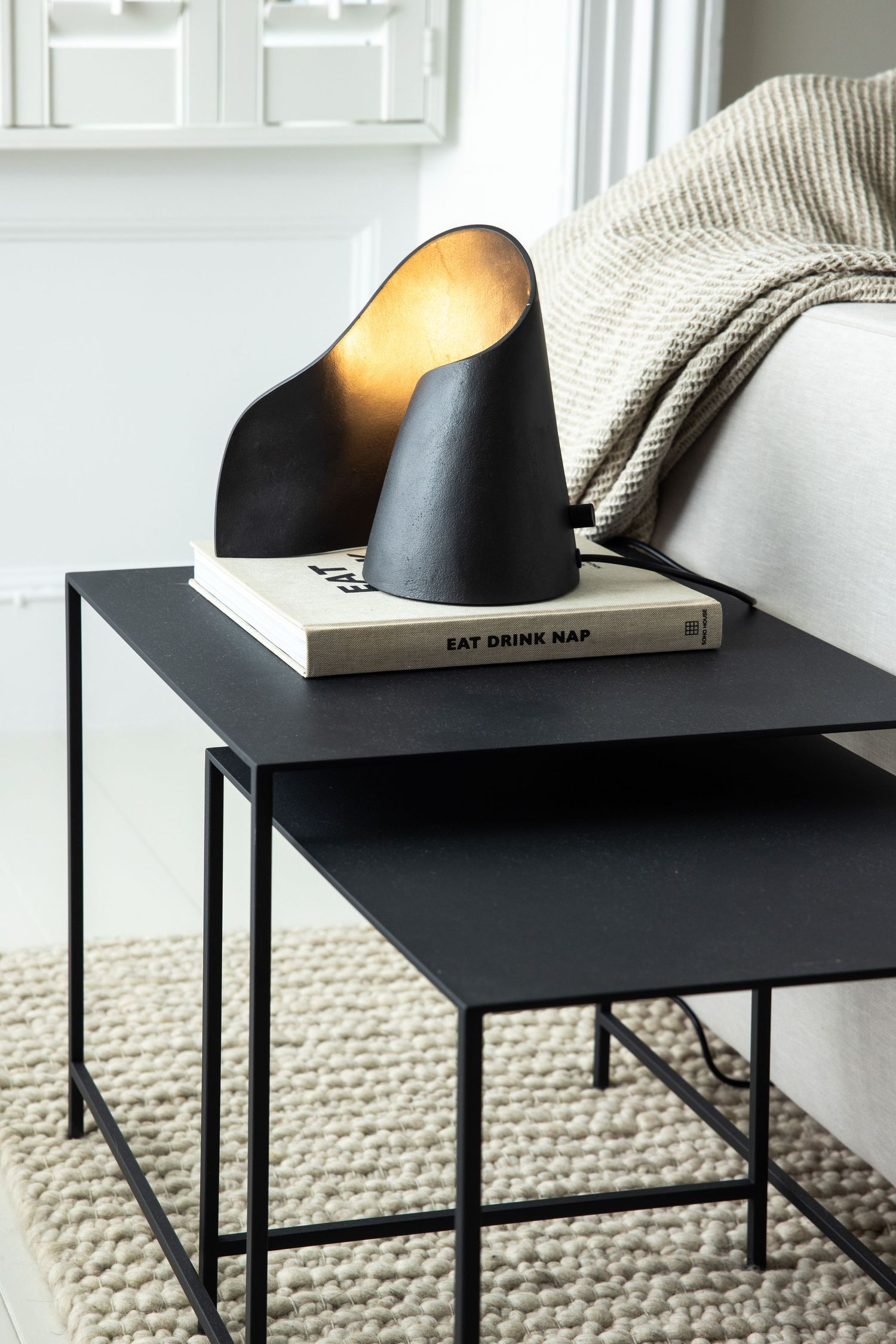 Modern black side tables with geometric lamps in a contemporary living space.