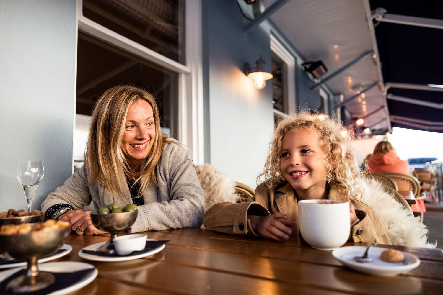 Cozy cafe setting with coffee cups and pastries on a white table in natural light.