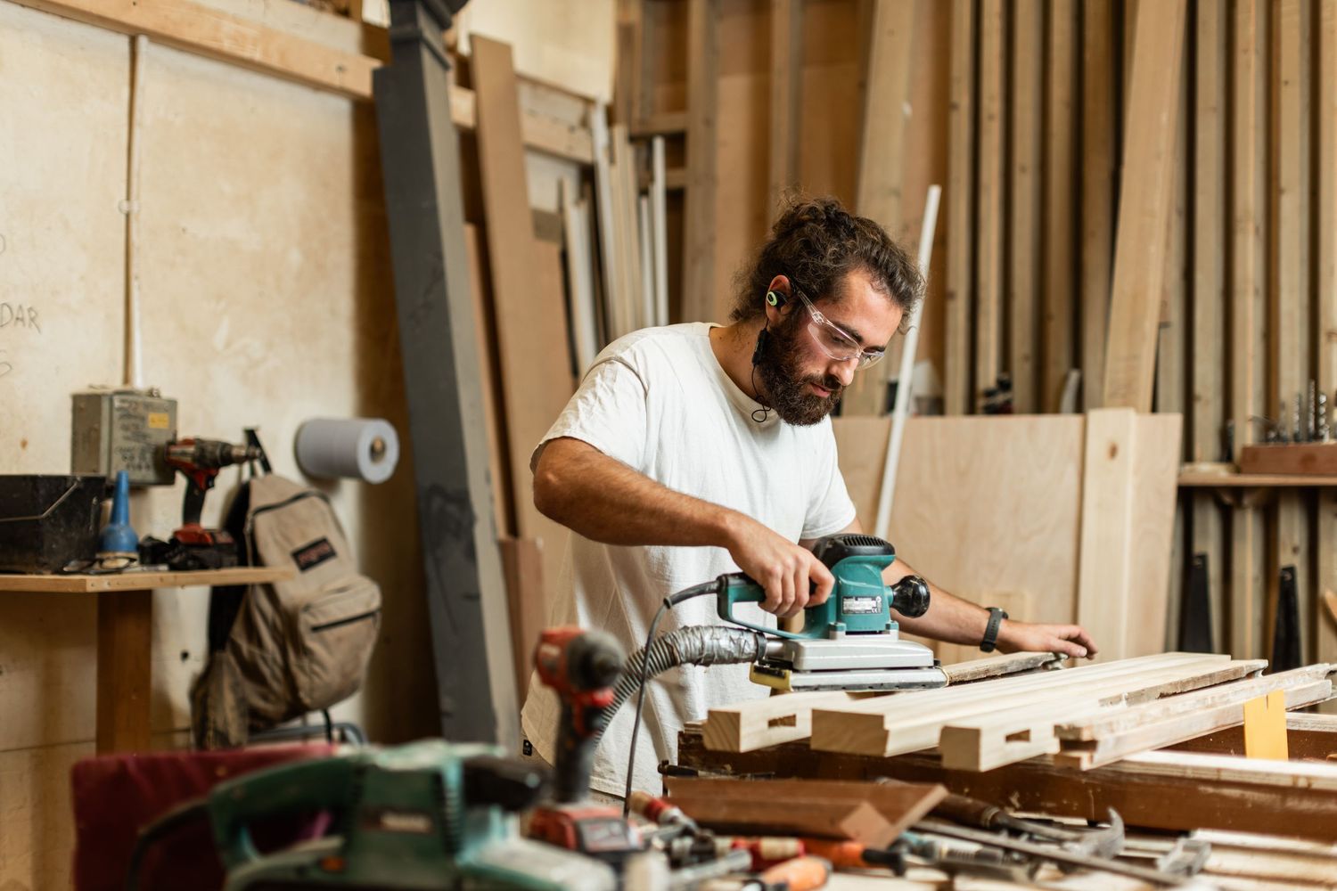 Professional woodworking shop with craftsmen using various power tools and equipment.
