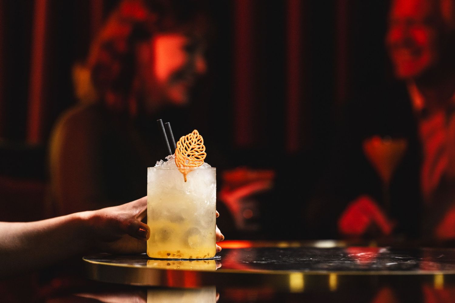 Artistic cocktail presentation with red lighting and dramatic smoke effects at an upscale bar.