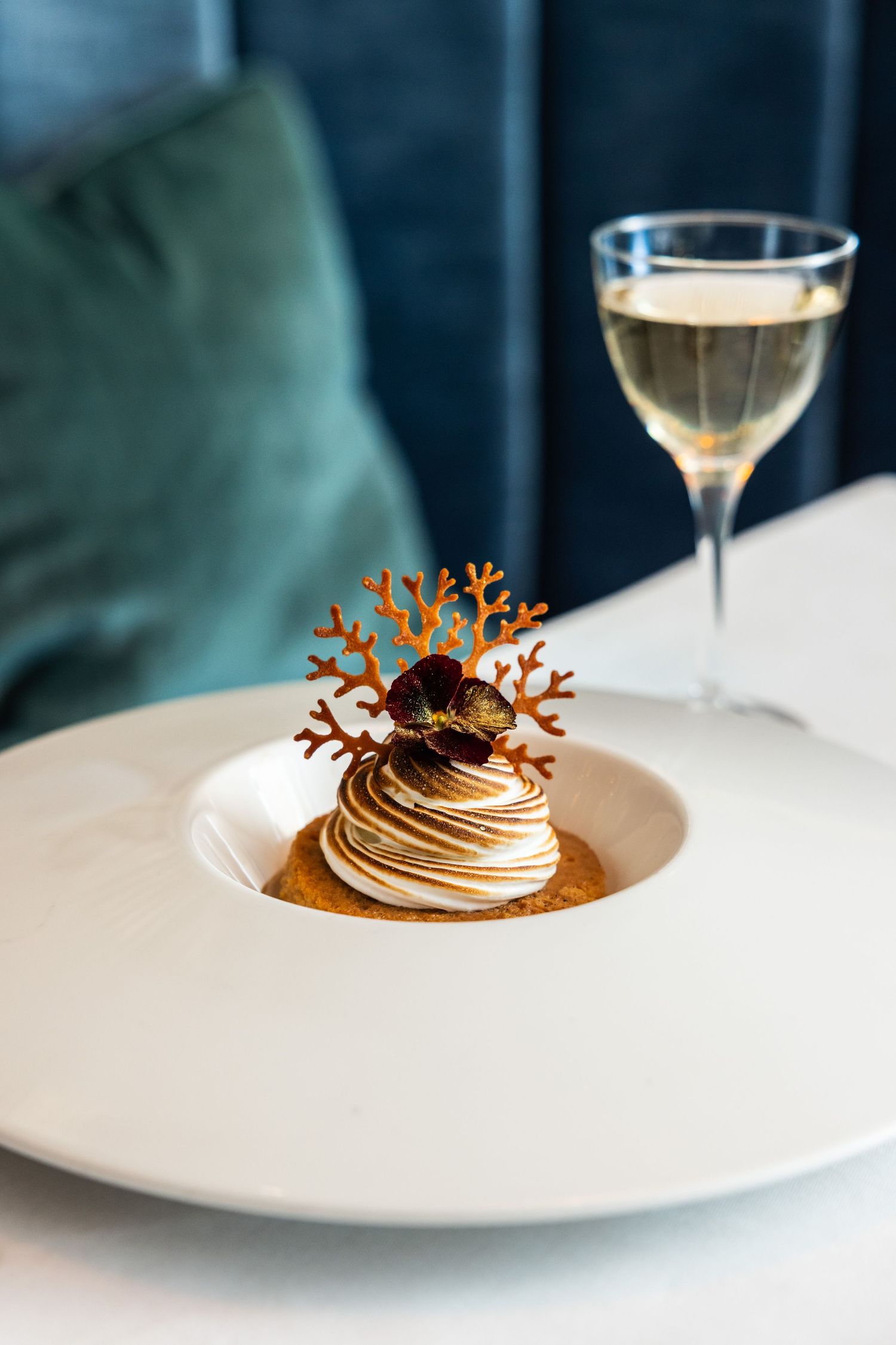Artistic dessert presentation featuring a swirled chocolate creation with decorative coral garnish.