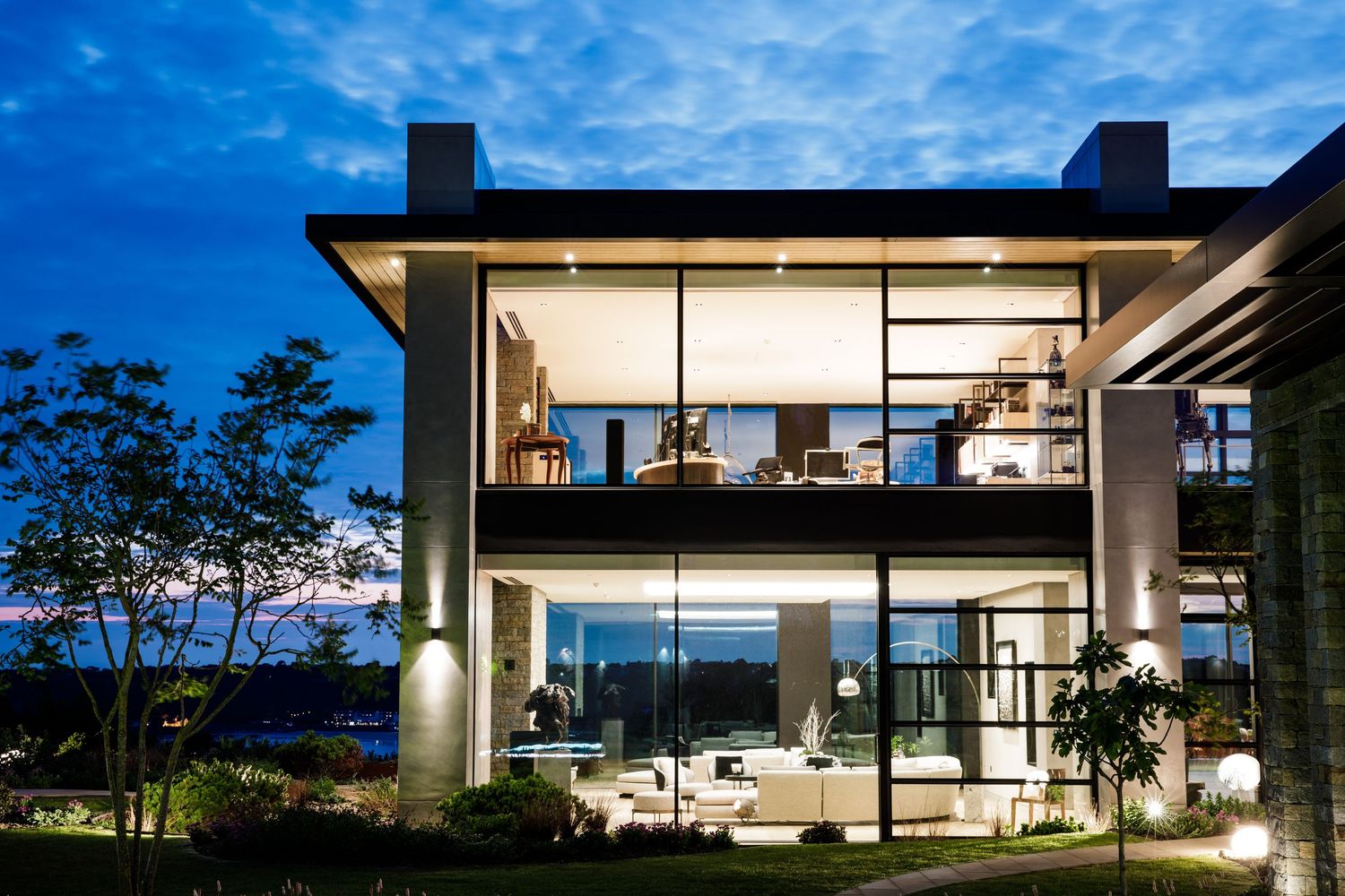 Modern luxury house exterior with large windows and clean architectural lines at dusk.