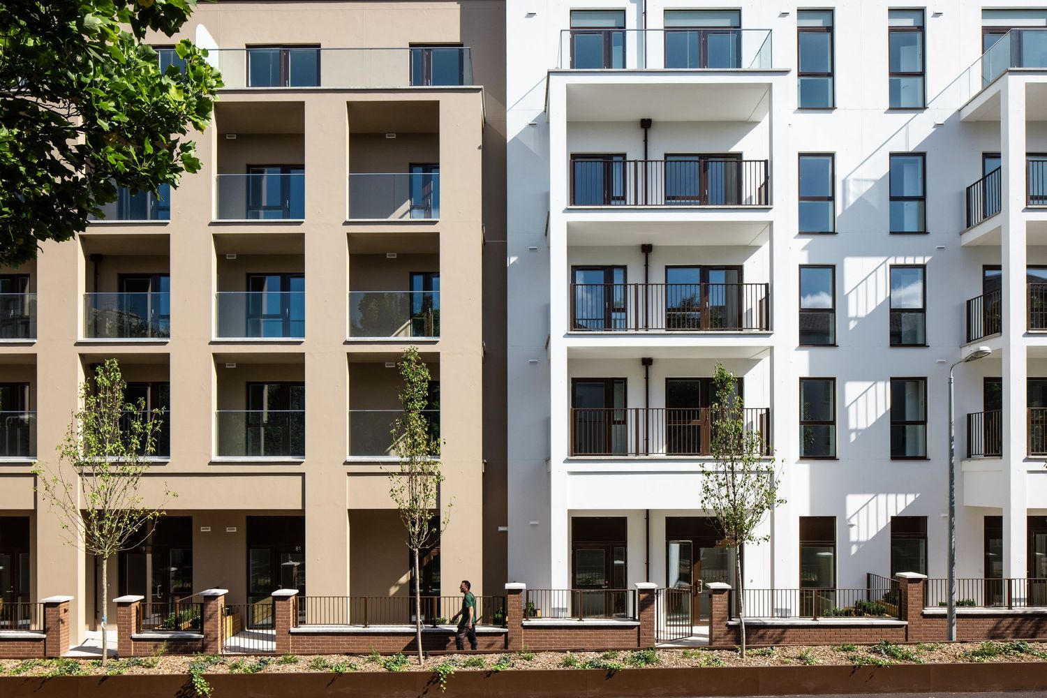 Contemporary residential buildings with alternating tan and white facades featuring uniform balconies.