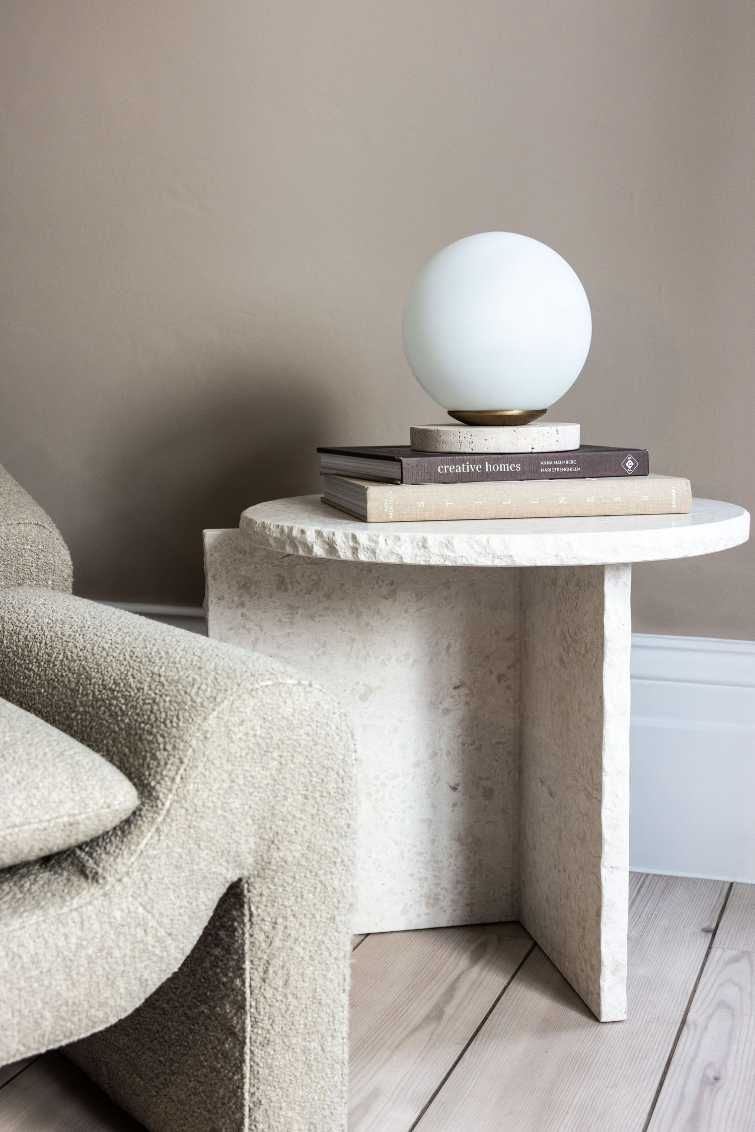 Textured cream-colored curved bench with spherical lamp and book styling.