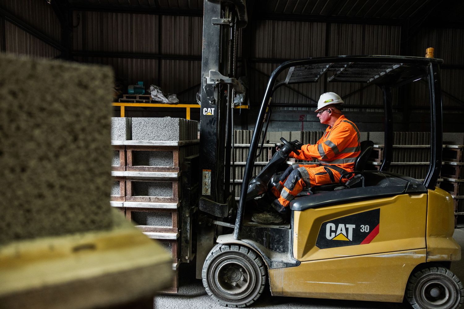 Yellow CAT forklift machinery being operated in a warehouse facility.
