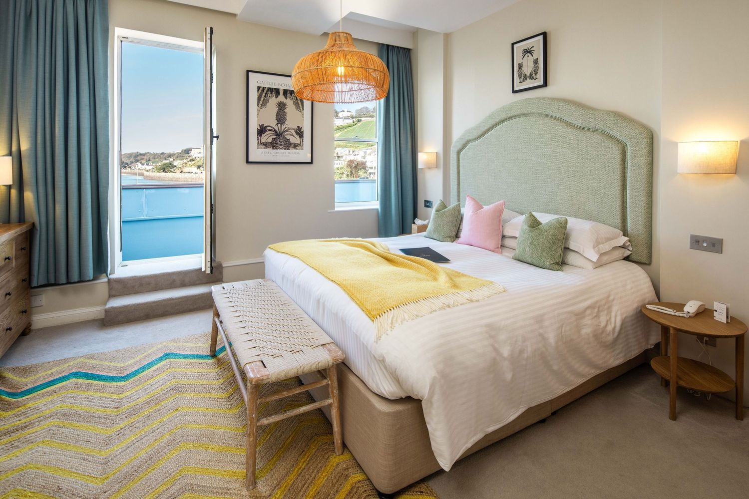Modern coastal hotel room interior with soft blue decor and ocean view windows.