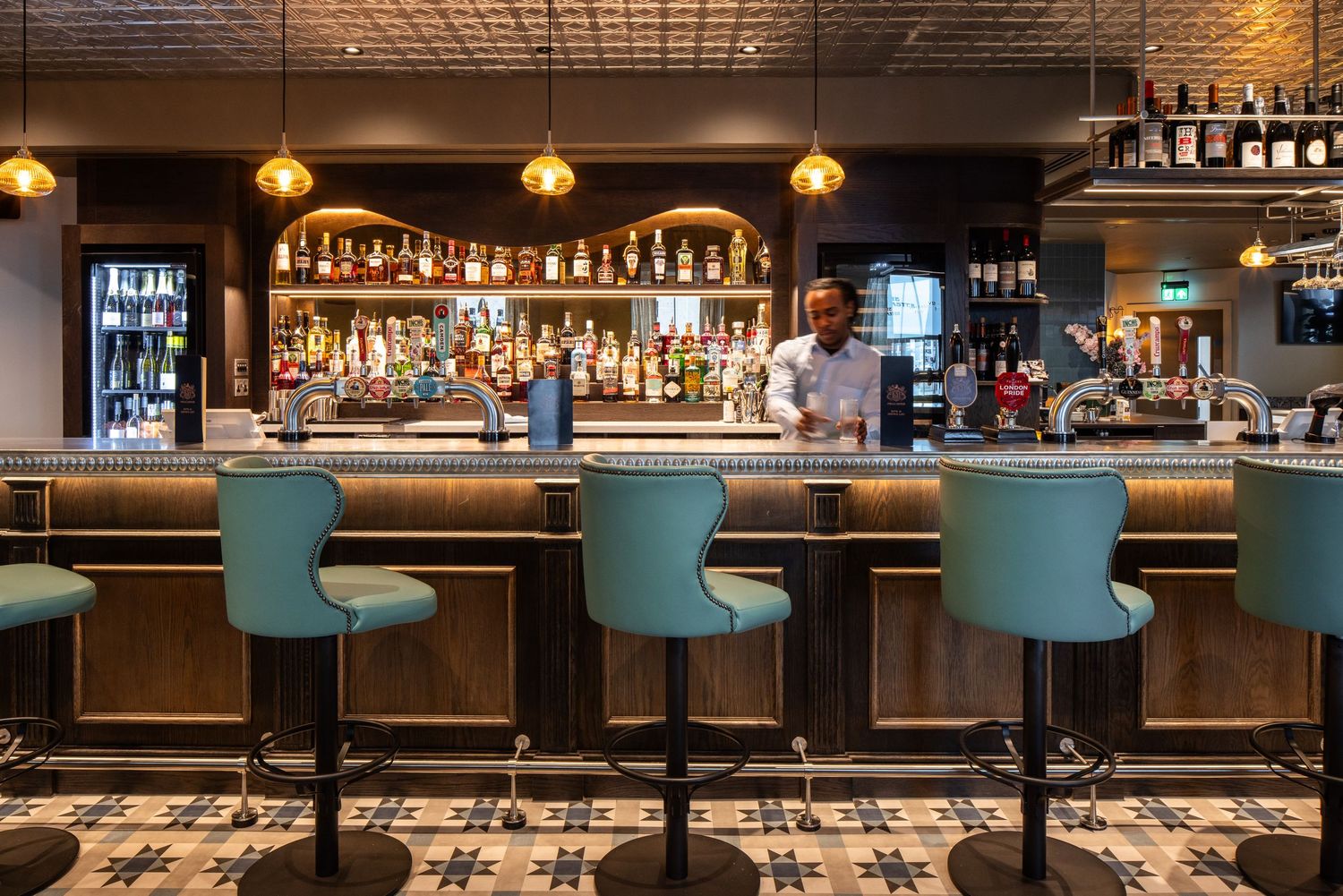 Stylish bar interior with turquoise bar stools and warm pendant lighting above wooden counter.
